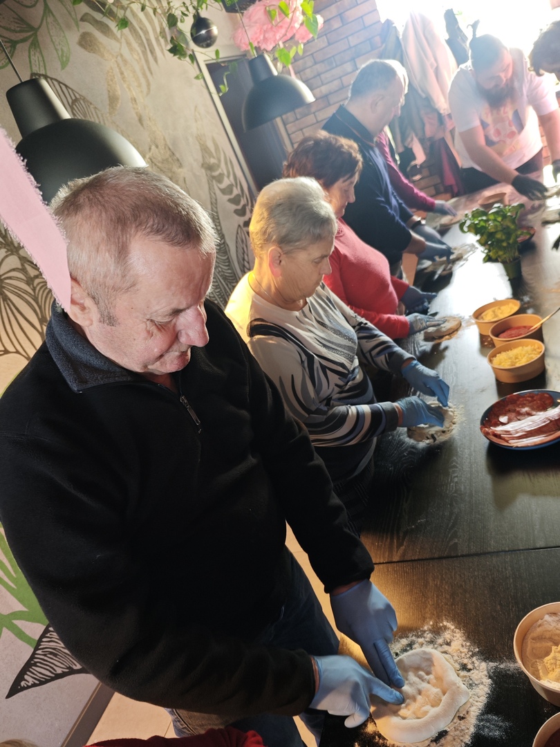 Zdjęcie przedstawia jednego seniora wyrabiającego ciasto na pizze