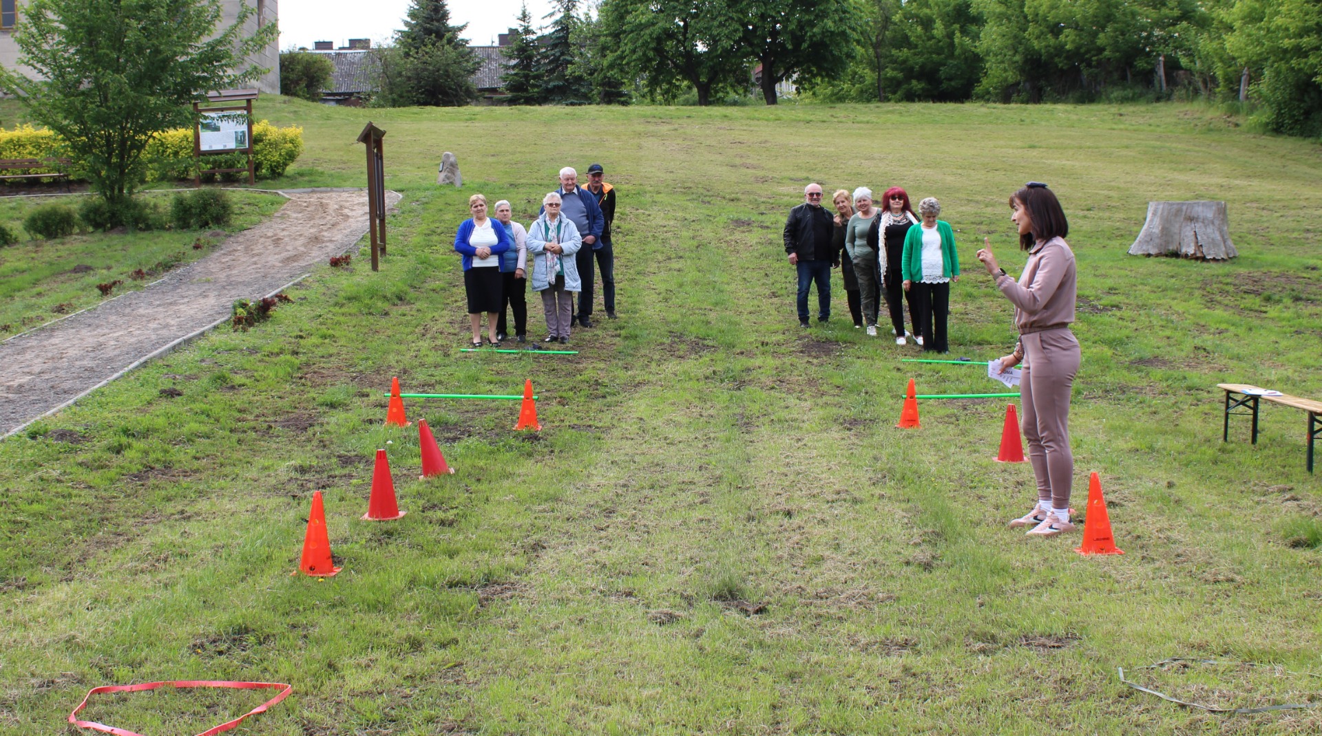 Fotografia przedstawia uczestników konkurencji ruchowej zorganizowanej podczas Majówki Seniora, którzy mierzą się z przygotowanym torem przeszkód
