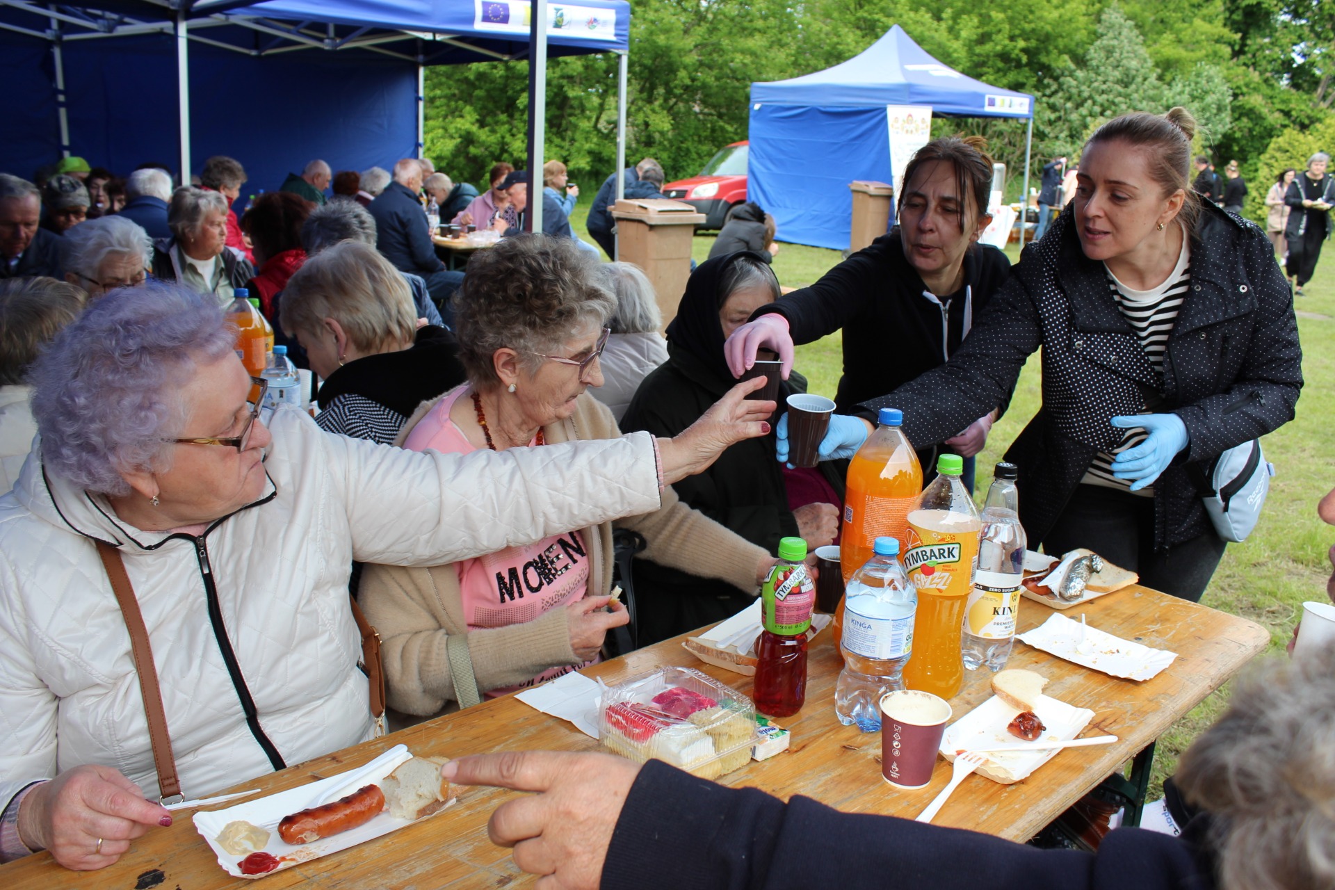Na zdjęciu zobaczyć możemy Seniorów podczas wspólnego posiłku – tj. kiełbaski i kaszanki z grilla