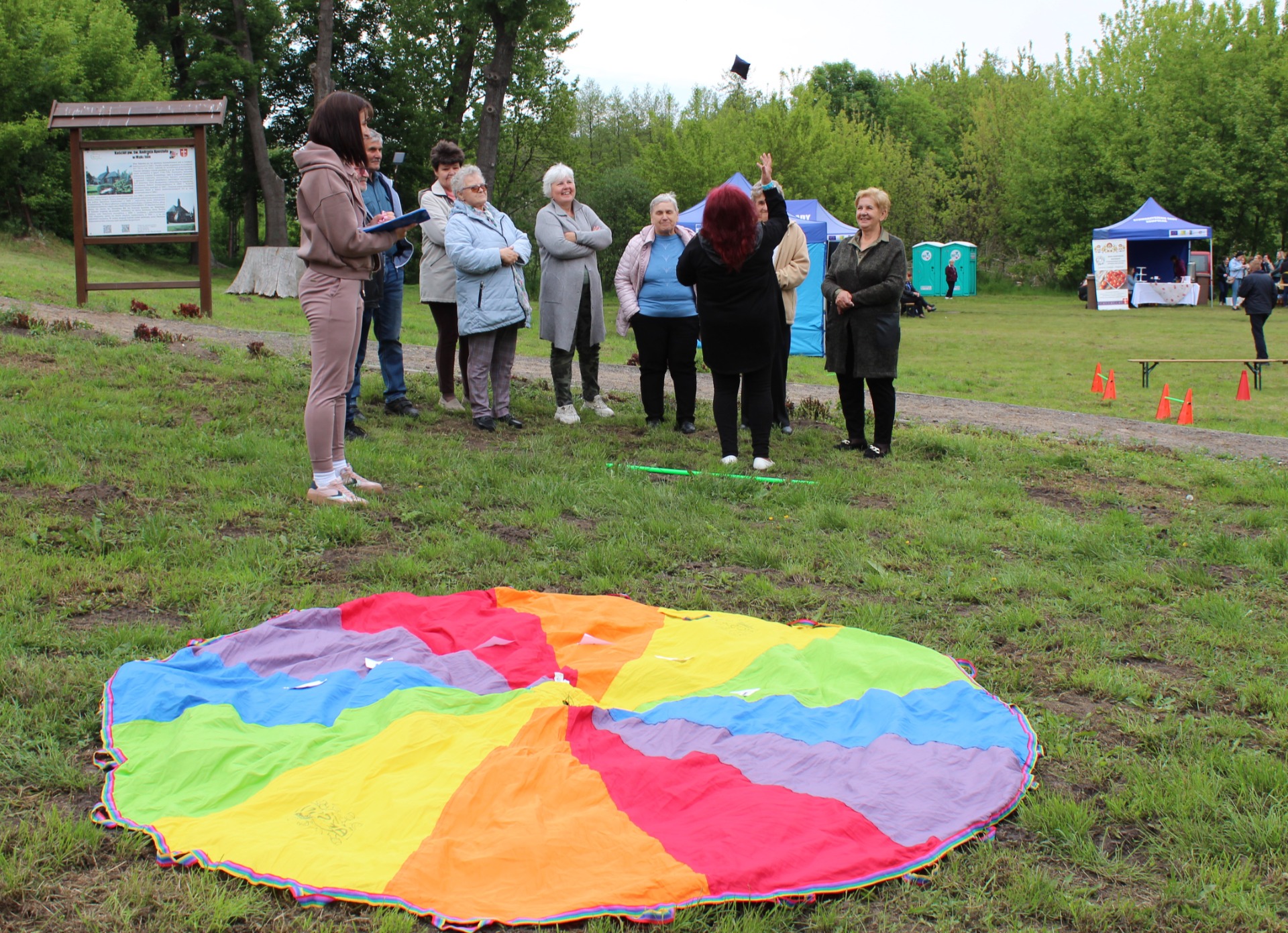 Zdjęcie przedstawia Seniorów zmagających się podczas konkurencji ruchowej , której celem było trafienie woreczkiem do celu.