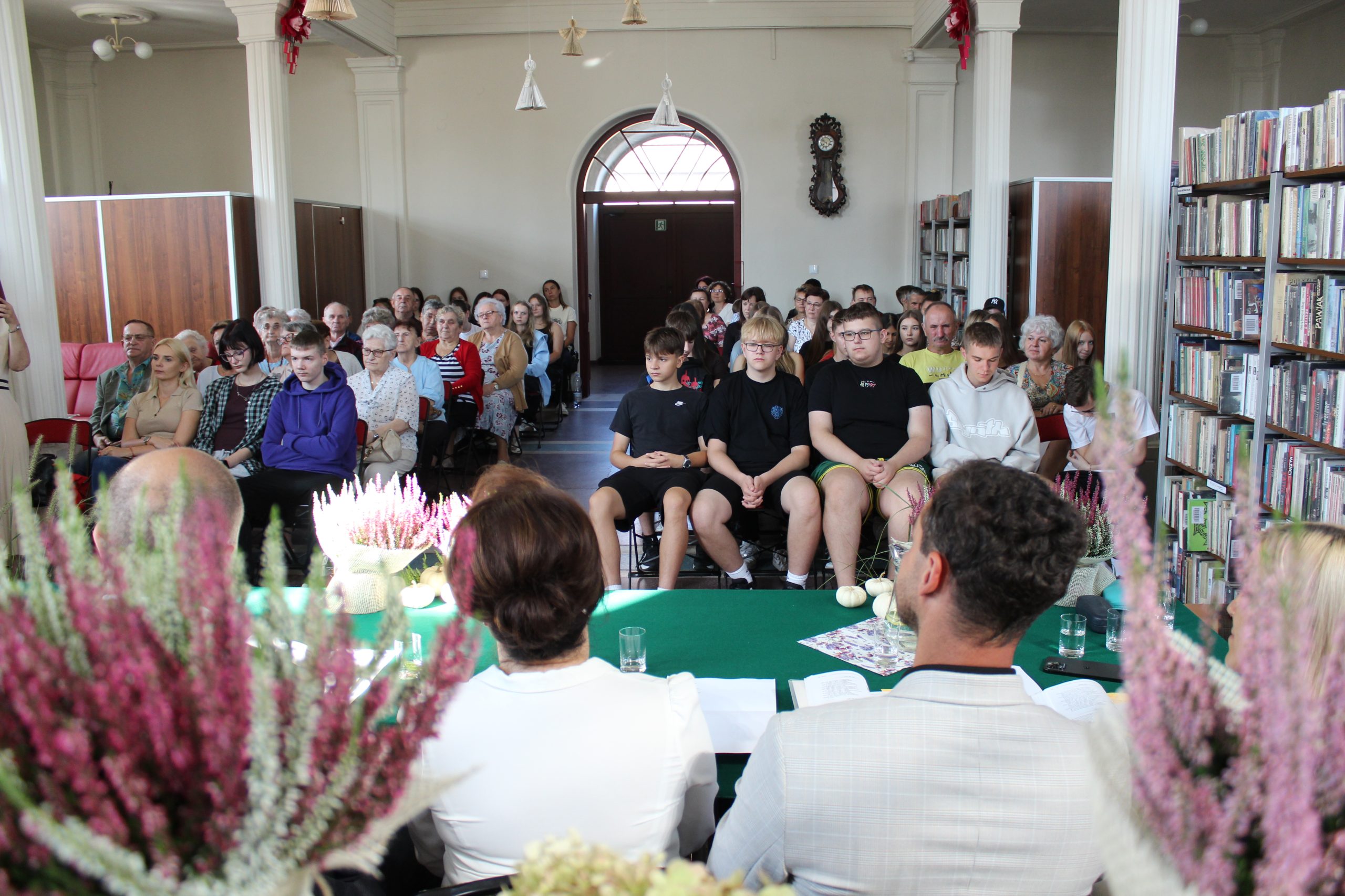 Zdjęcie przedstawia słuchaczy siedzących w bibliotece