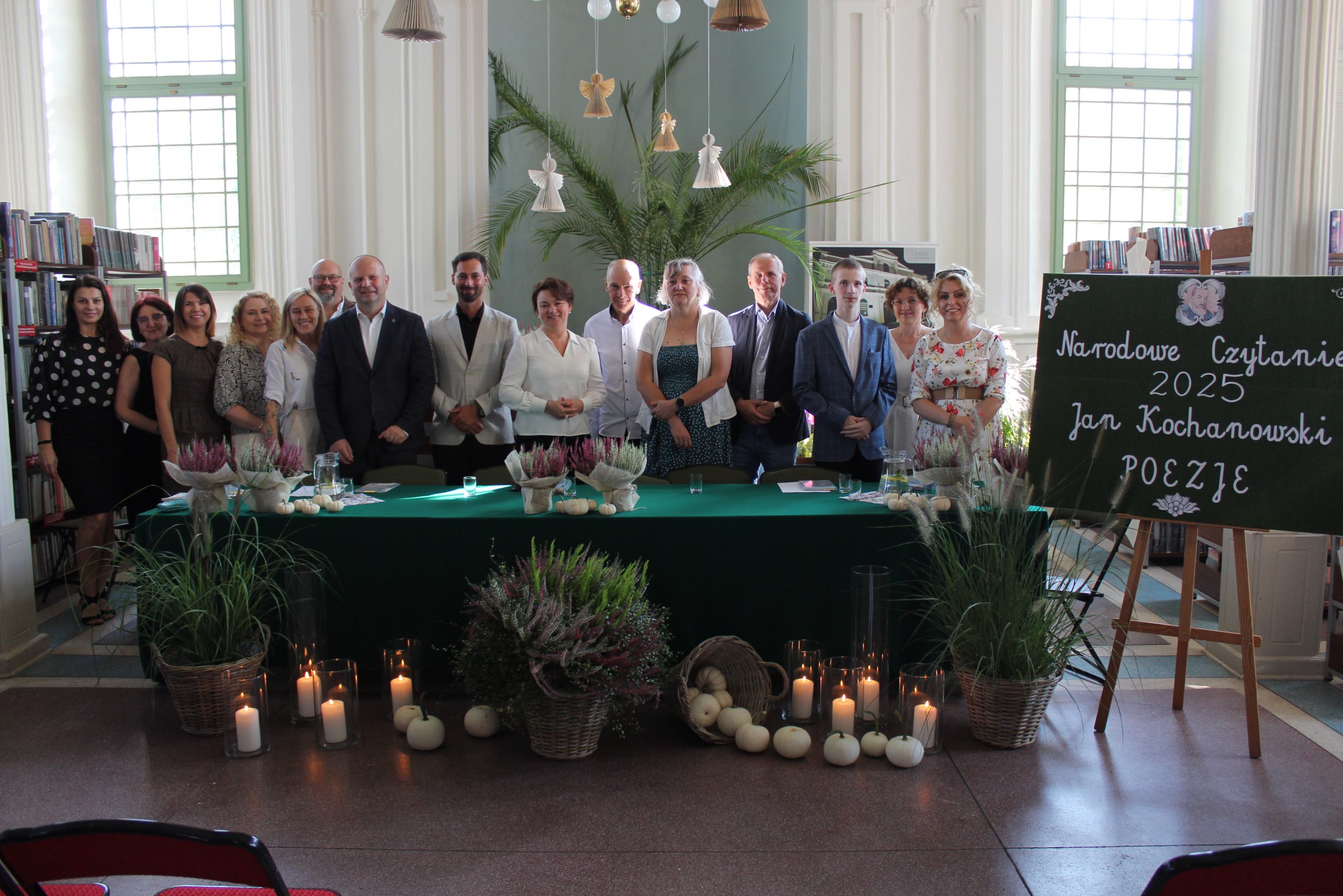 Zdjęcie grupowe we wnętrzu biblioteki przedstawiające wszystkich czytających