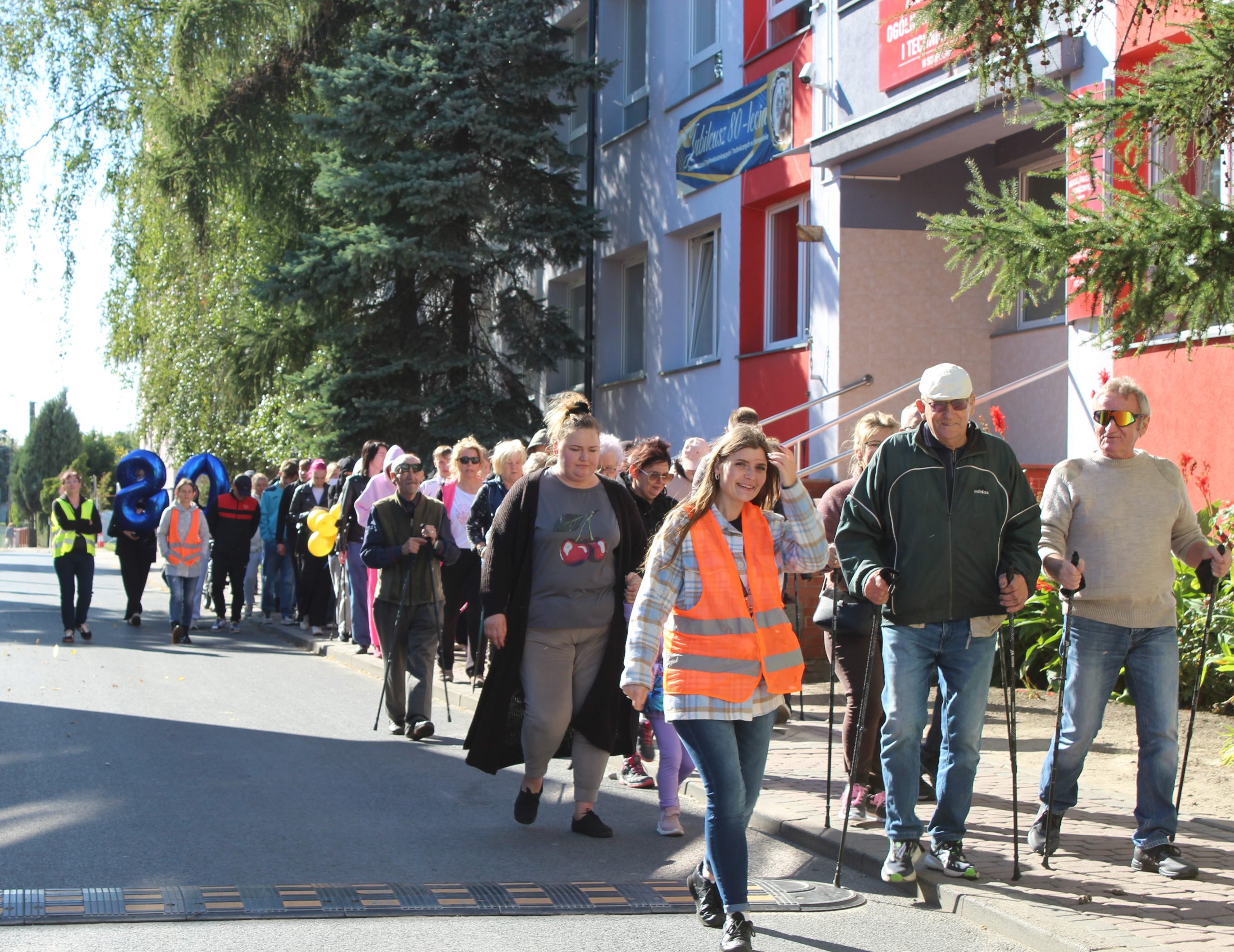 Zdjęcie przedstawia uczestników marszu idących ulicą Gimnazjalną. W tle Zespół Szkół Ogólnokształcących i Technicznych,