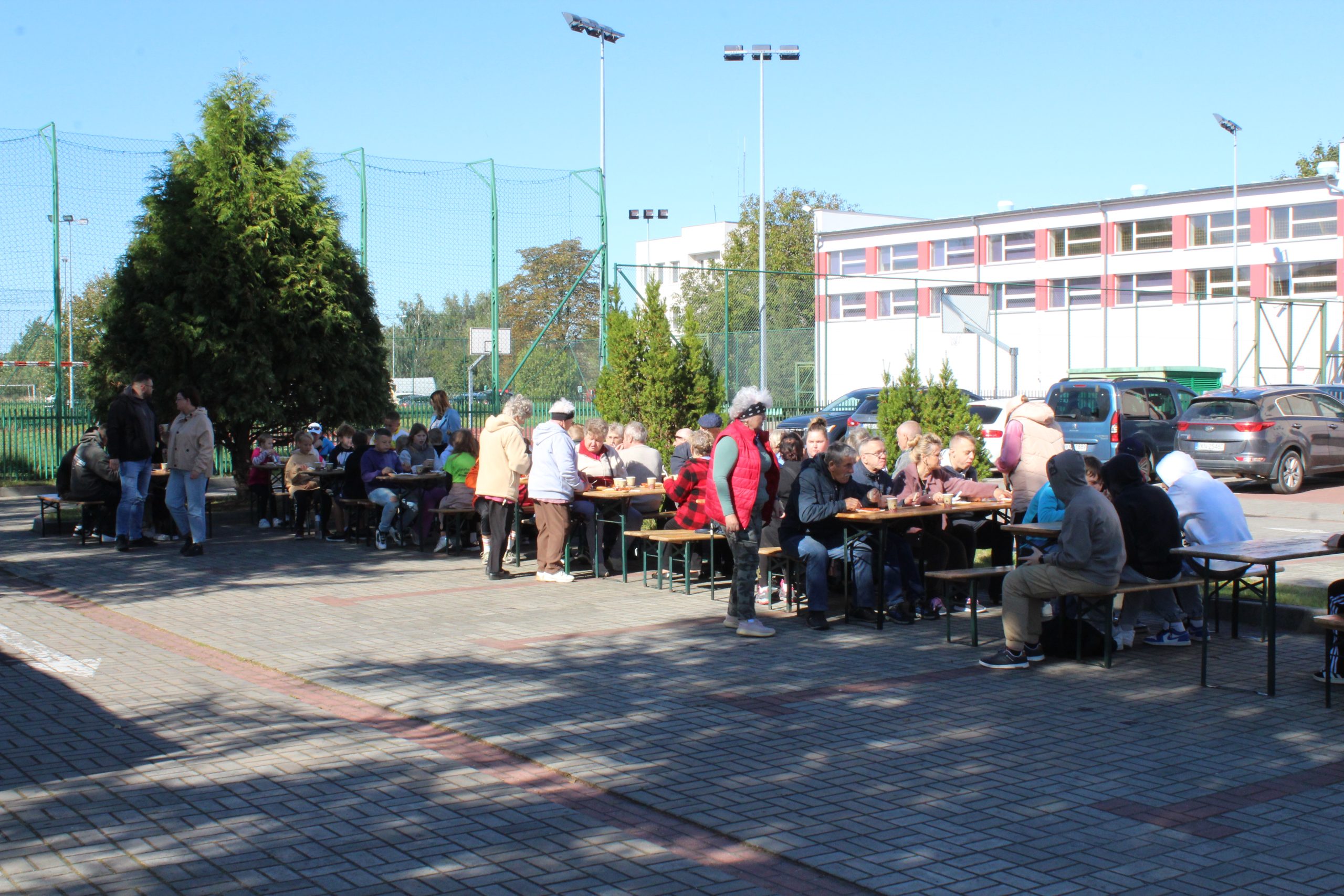 Zdjęcie przedstawia uczestników marszu odpoczywających przy stołach