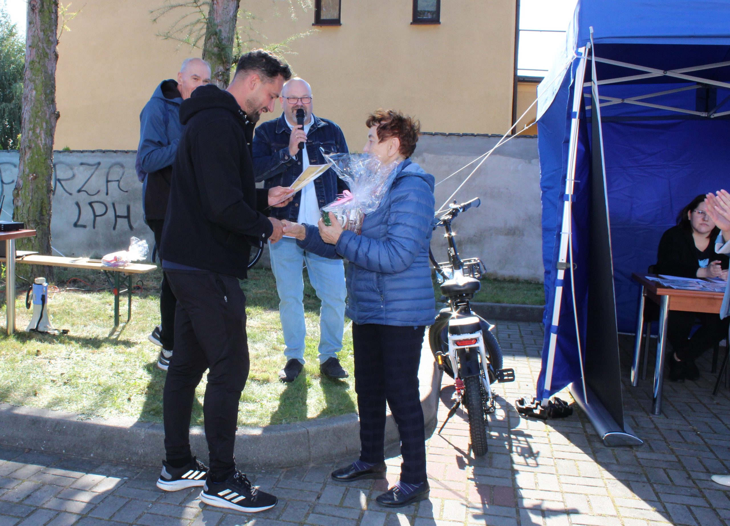 Na fotografii dyplom i upominek otrzymuje najstarsza uczestniczka marszu