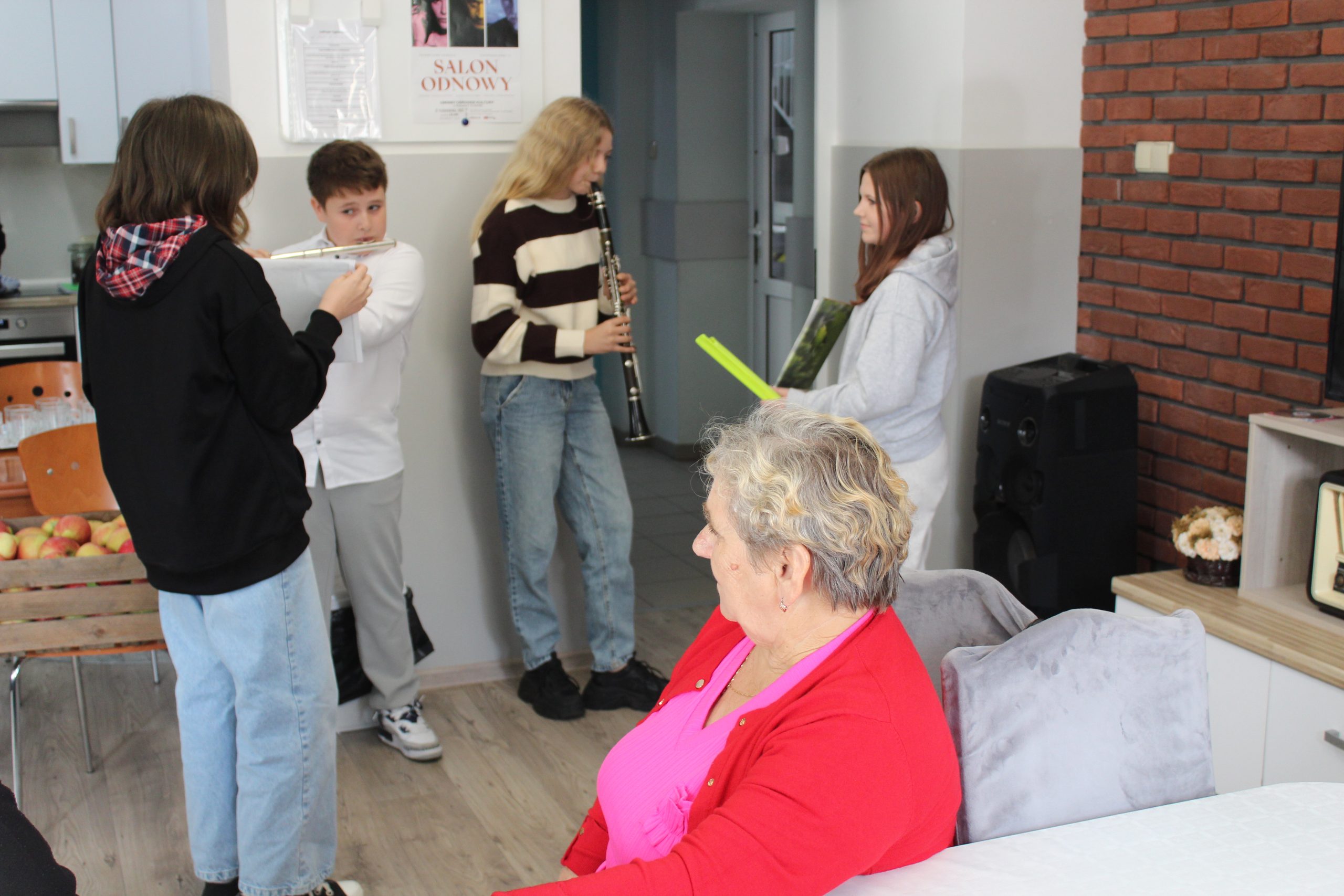 Zdjęcie wykonane w domu sali głównej Domu Dziennego Pobytu – przedstawia dzieci grające na instrumentach