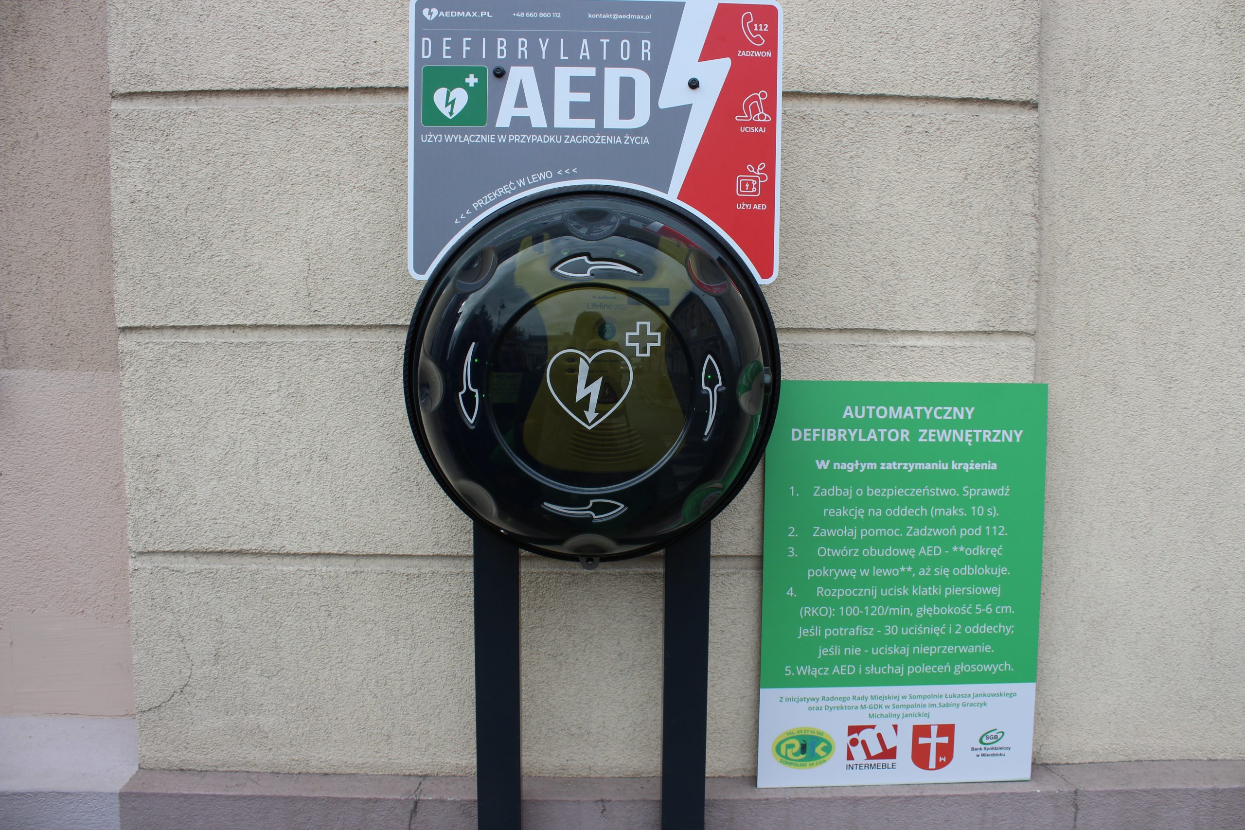 2) Na zdjęciu widać sprzęt AED który znajduje się na zewnątrz budynku MGOK w Sompolnie