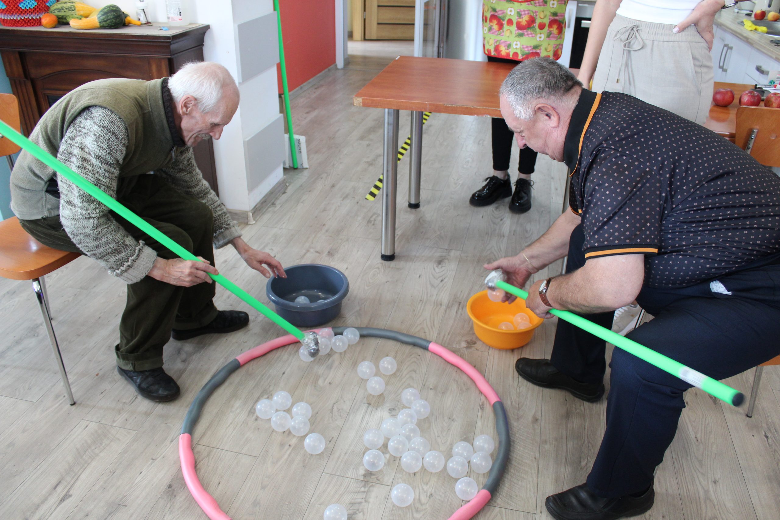 2) Zdjęcie przedstawia dwóch Panow – uczestników DDP konkurujących ze sobą podczas zabawy ruchowej.