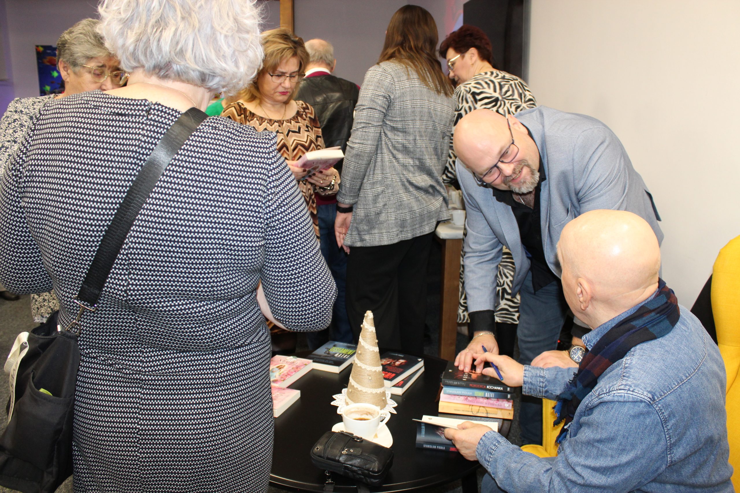 5. Zdjęcie przedstawia Stanisława Pigułę, który podpisuje dedykacje do swoich książek dla chętnych uczestników.