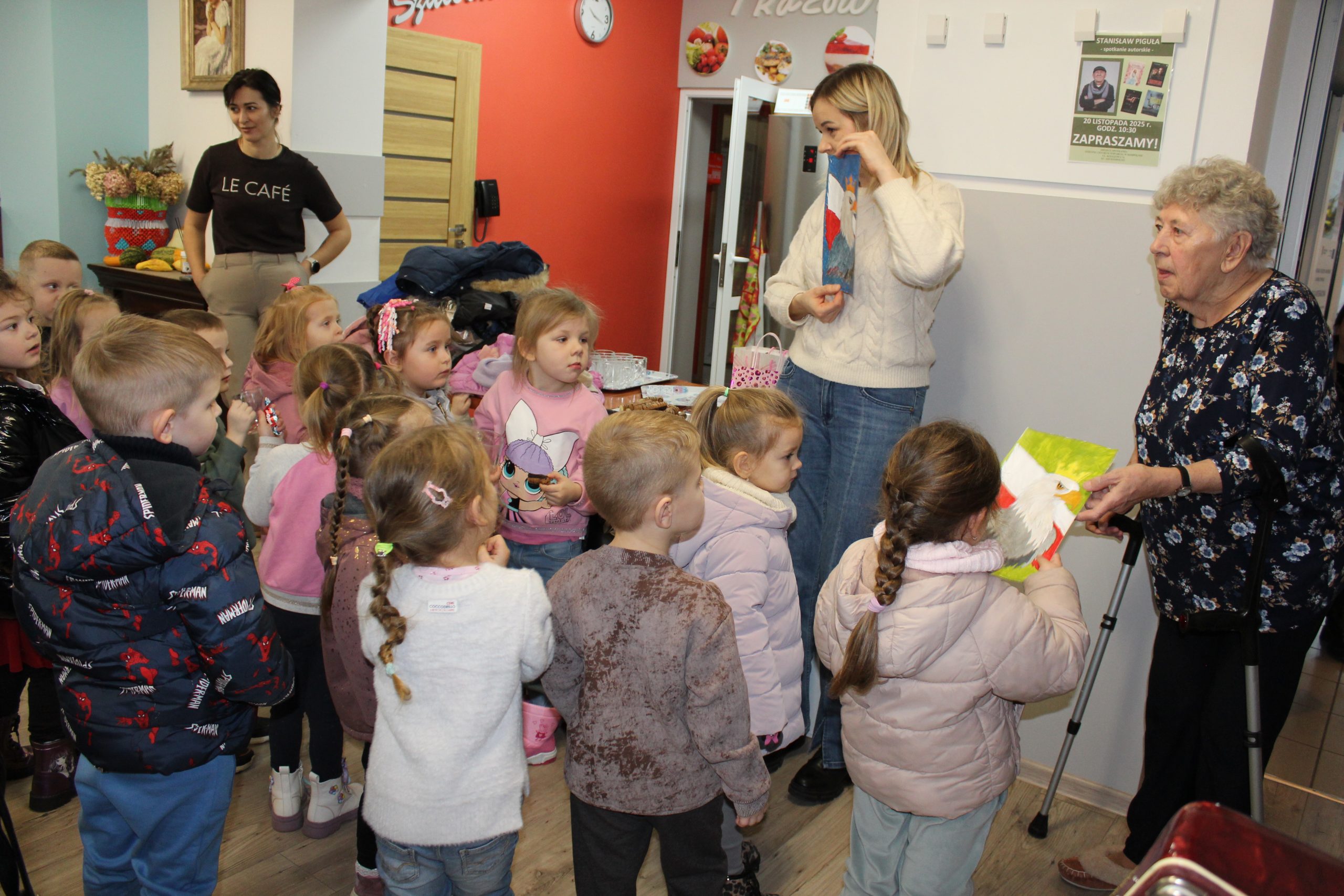 6. Na zdjęciu Pani przedszkolanka przedstawia dzieciom prace plastyczne wykonane przez seniorów