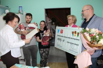 1) Zdjęcie wykonane w domu rodziców trojaczków. Przedstawia rodziców, dzieci oraz przedstawicieli urzędu.