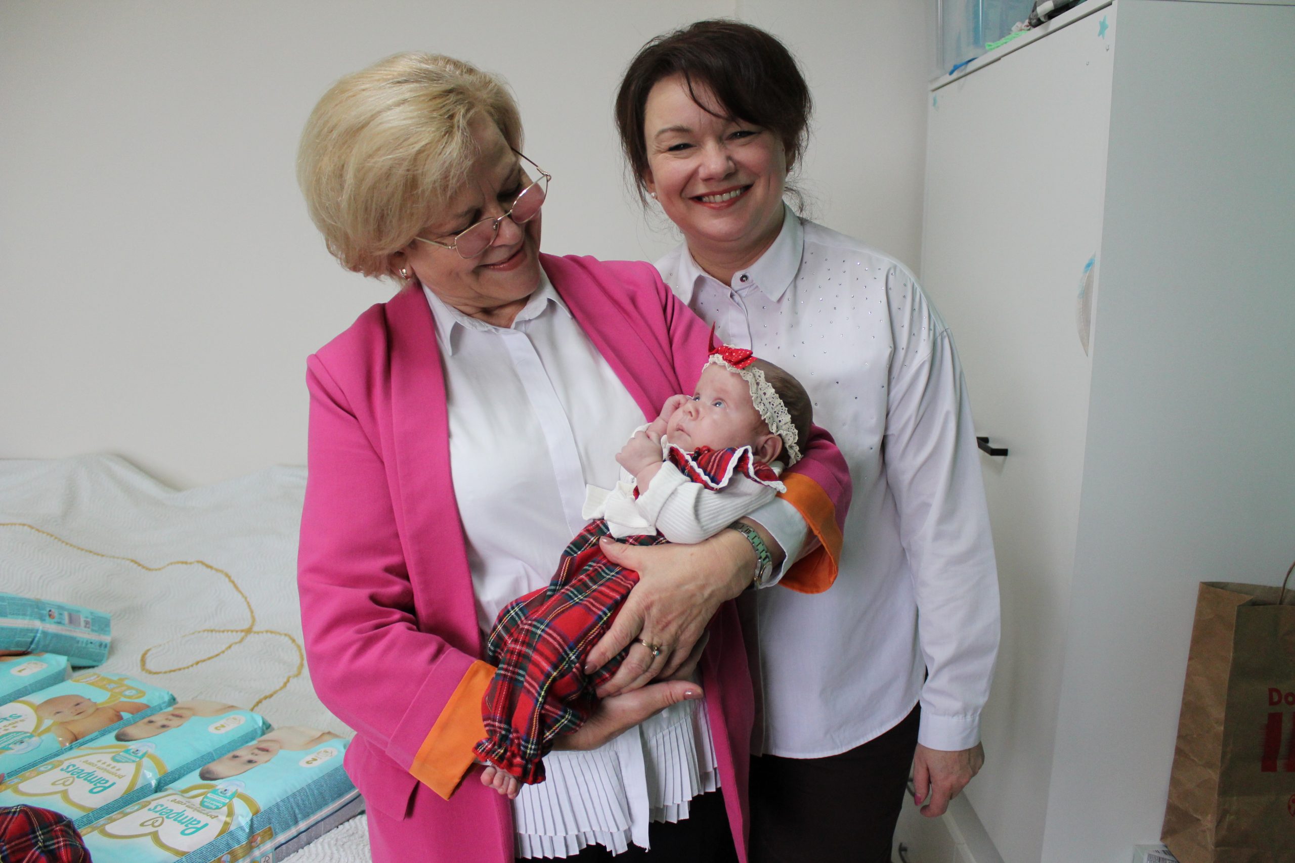 5) Zdjęcie przedstawia przedstawicielki urzędu. Jedna z nich trzyma na ręcach dziecko.