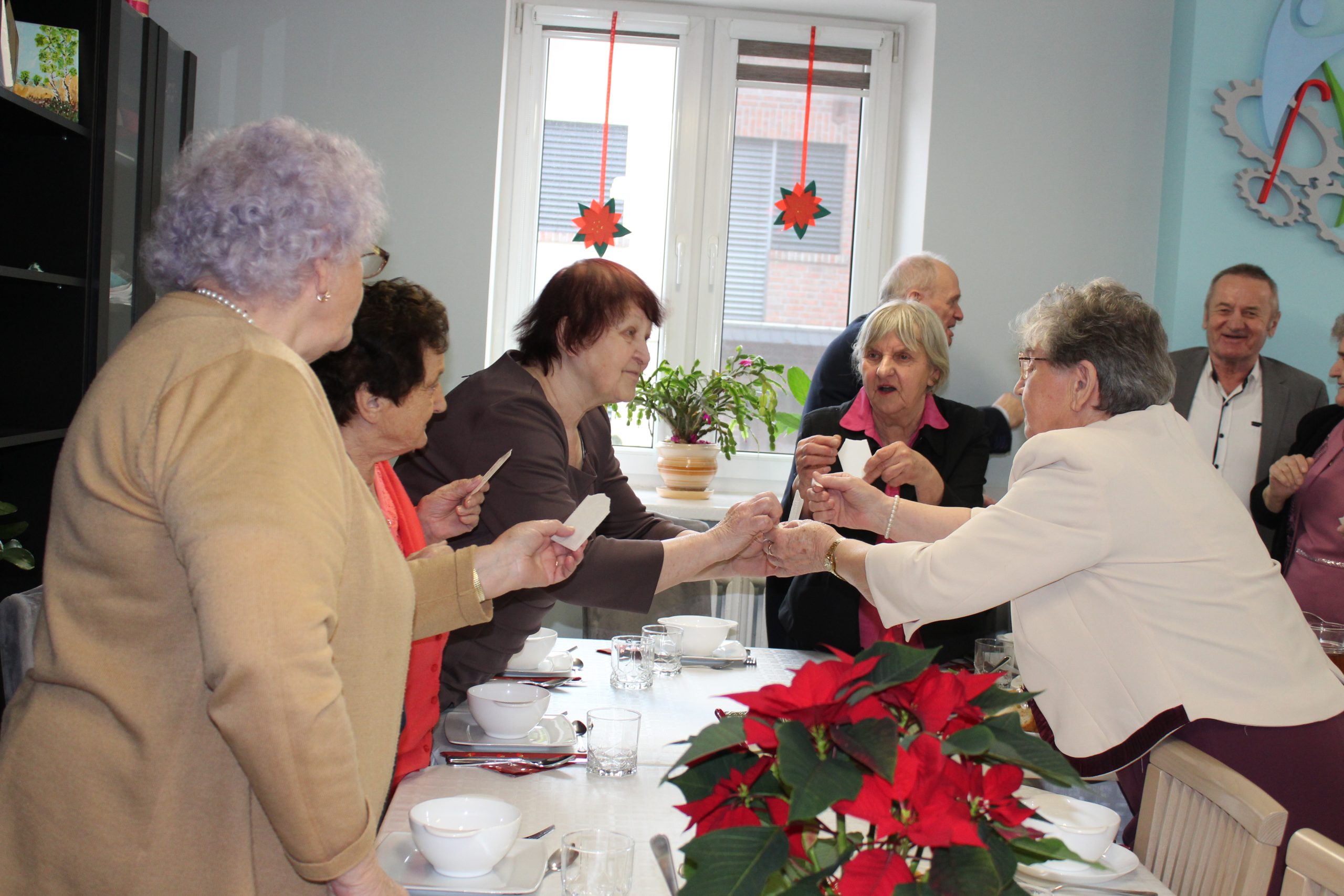 4) Zdjęcie przedstawia seniorów dzielących się opłatkiem.