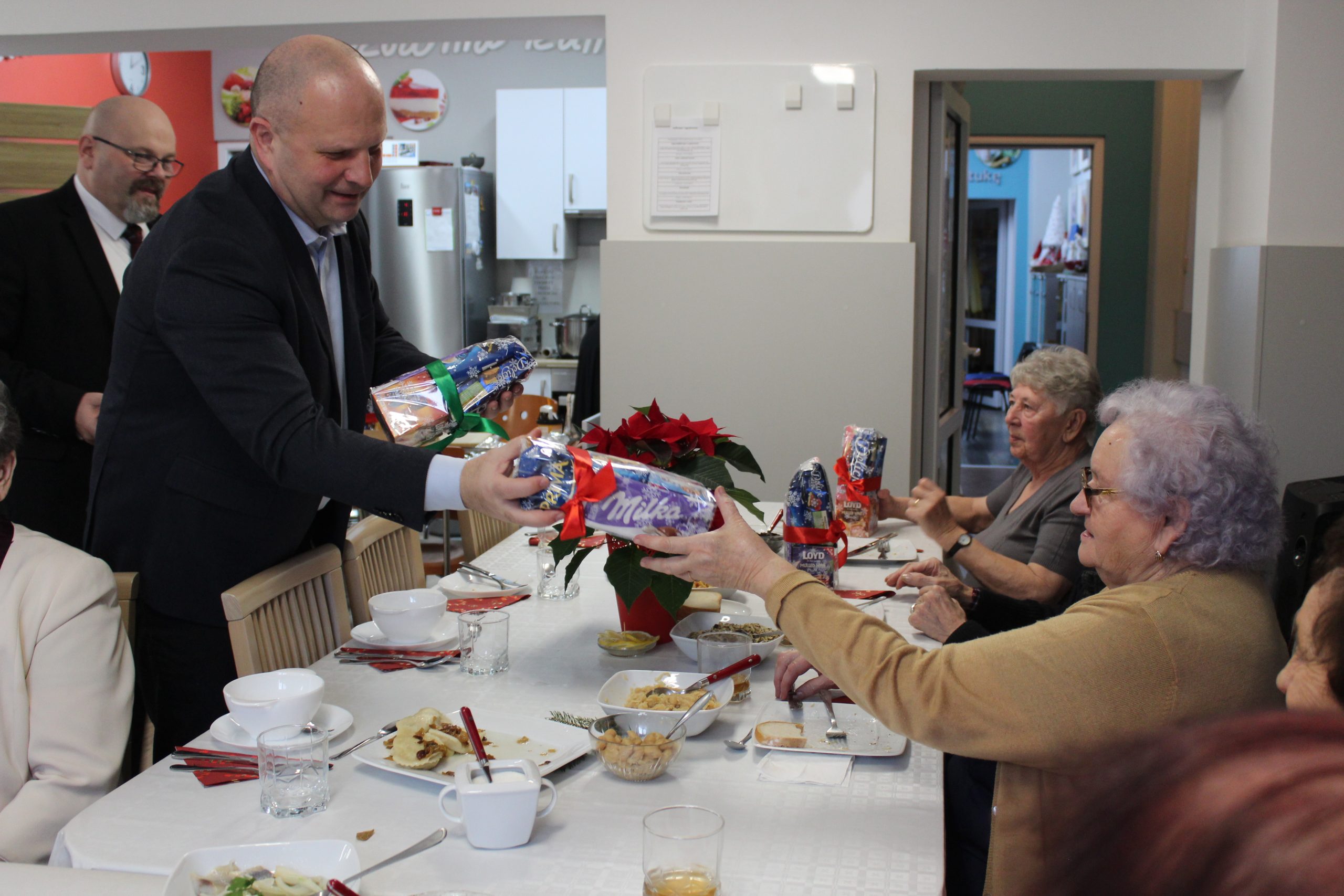 5) Na fotografii burmistrz wręczający słodkie upominki seniorom.