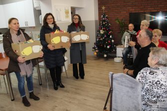 1) Zdjęcie wykonane w sali głównej Domu Dziennego Pobytu w Sompolnie. Przedstawia nauczycielki ze szkoły w Mąkolnie, które przyniosły kartony z herbatką dla seniorów.