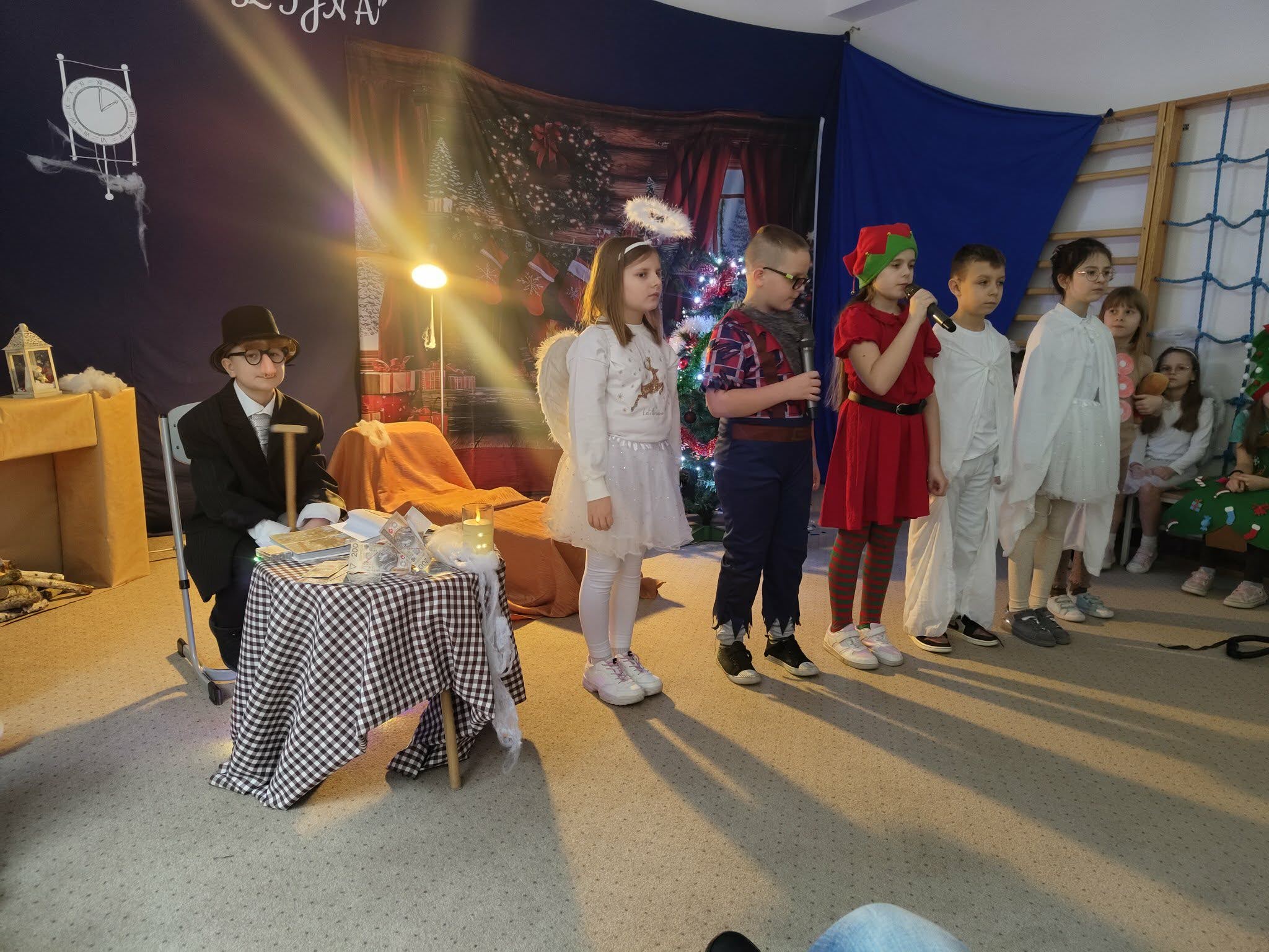 Zdjęcie przedstawia dzieci z klas drugich podczas przygotowanego dla seniorów przedstawienia pt „opowieść wigilijna”
