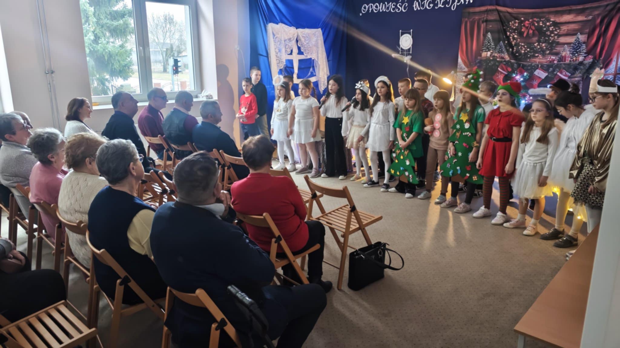 Na fotografii znajdują się seniorzy – widownia, oraz dzieci podczas występów przygotowanych dla uczestników DDP.