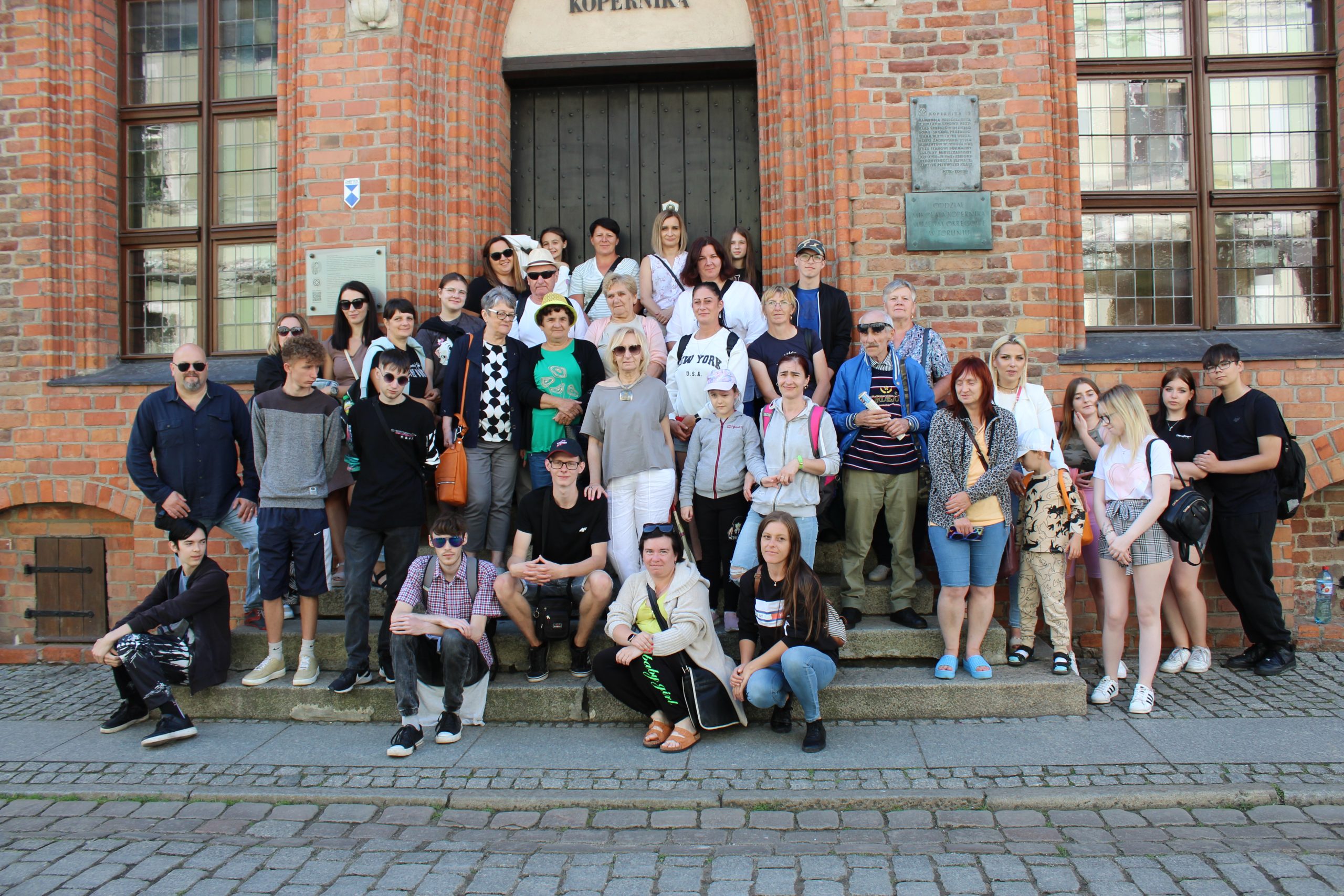 1) Zdjęcie grupowe przedstawiające wszystkich uczestników wycieczki do Torunia. Wykonane na schodach Domu Mikołaja Kopernika.
