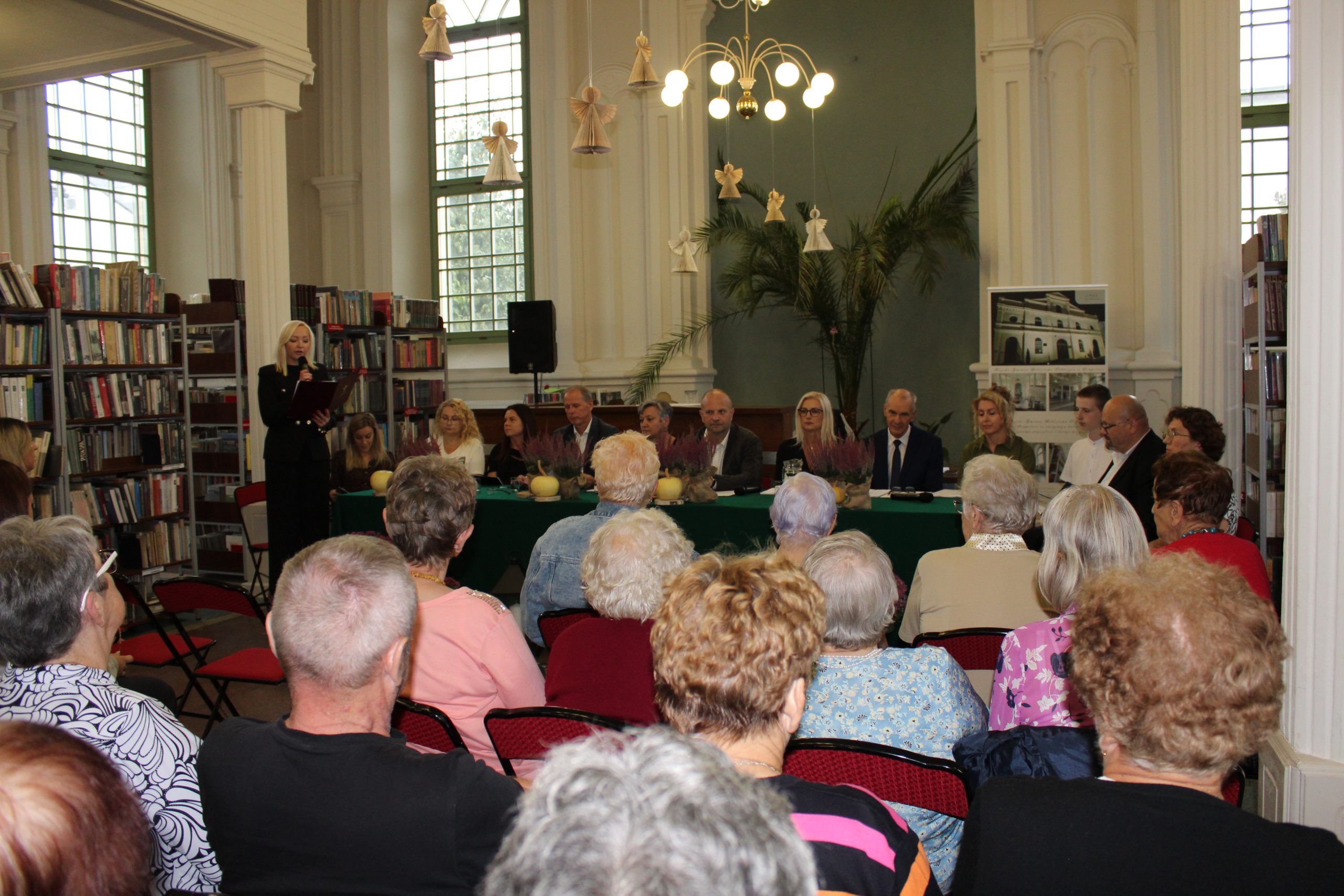 1. Zdjęcie wykonane w sali MGBP w Sompolnie. Przedstawia lektorów tegorocznego narodowego czytania, wśród nich Dyrektor MGBP w Sompolnie przemawiająca do zgromadzonych gości.