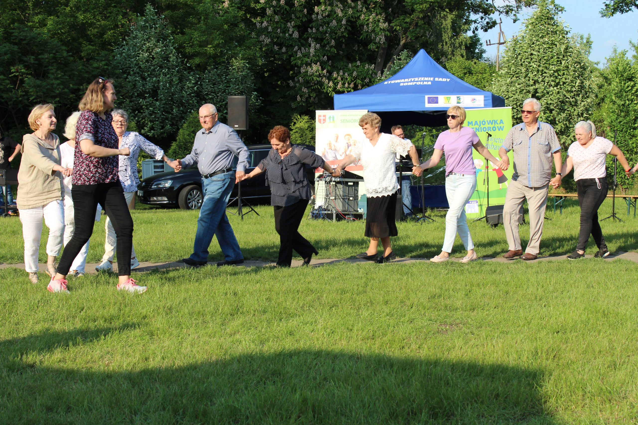 17) Seniorzy i pracownicy MGOPS tańczący na trawie.