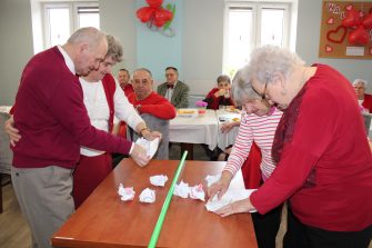 Zdjęcie wykonane podczas zabawy integracyjnej na balu karnawałowym w ddp. Przedstawia dwie pary uczestniczące w zabawie oraz seniorów w tle
