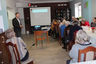 2) Na fotografii widać doktora Tomasza Pieńkowskiego tłumaczącego seniorom zagadnienia dotyczące rehabilitacji.