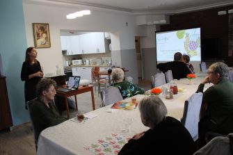 Zdjęcia przedstawia Panią dietetyk, która prowadzi zajęcia tematyczne dla grupy seniorów z DDP
