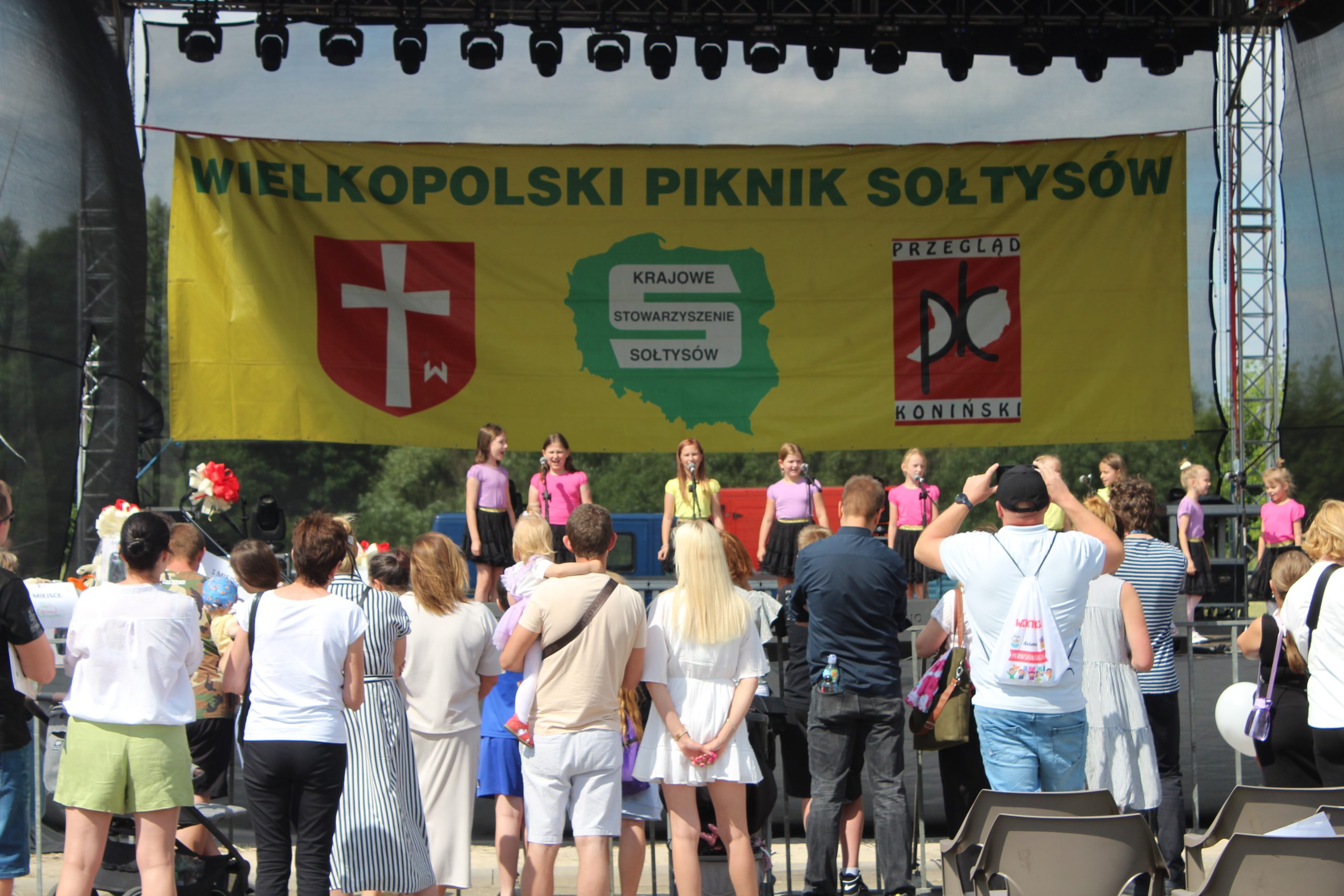 3. Fotografia przedstawia scenę, publiczność oraz młodych artystów podczas XXV Wielkopolskiego Pikniku Sołtysów,