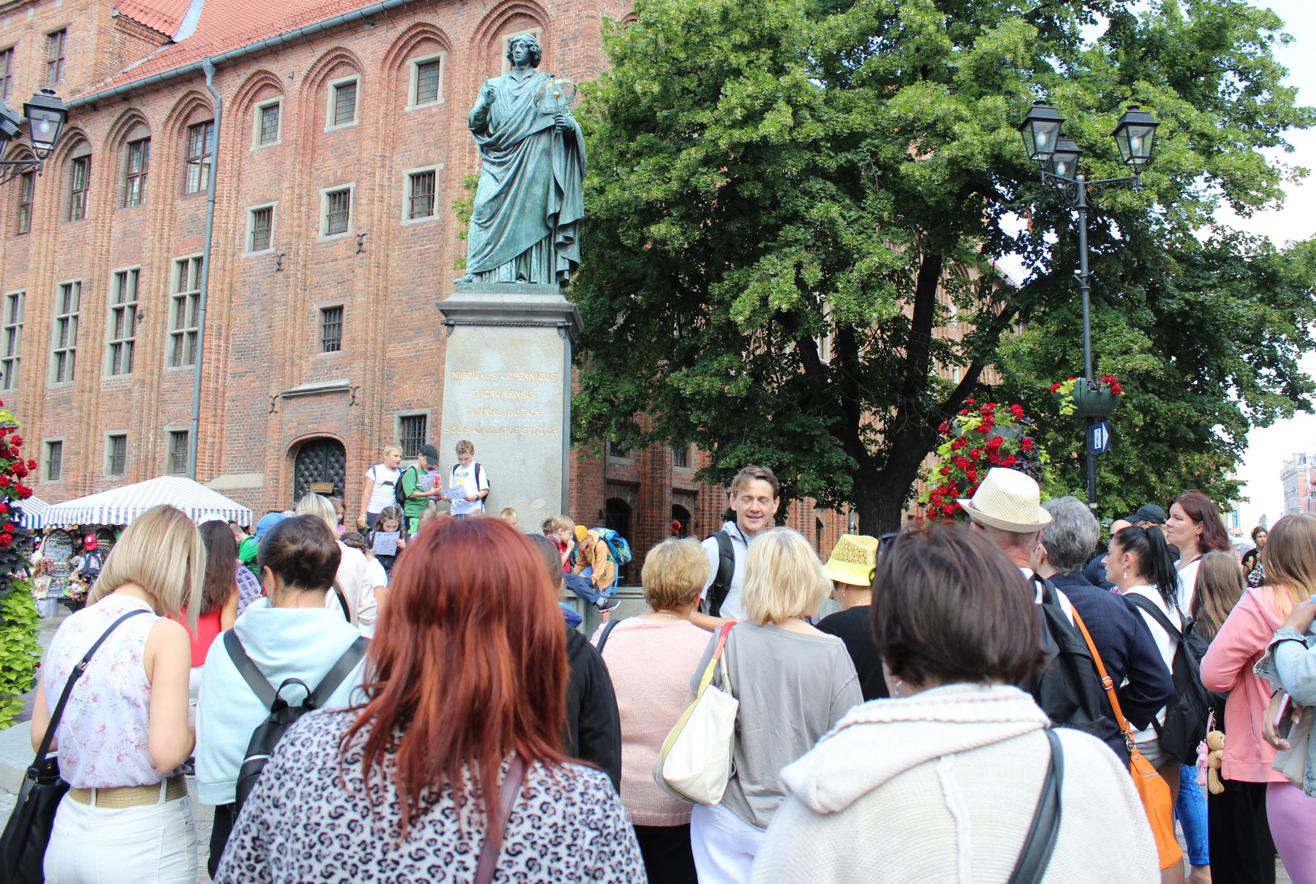 4) Fotografia przedstawia zwiedzających przy pomniku Mikołaja Kopernika.