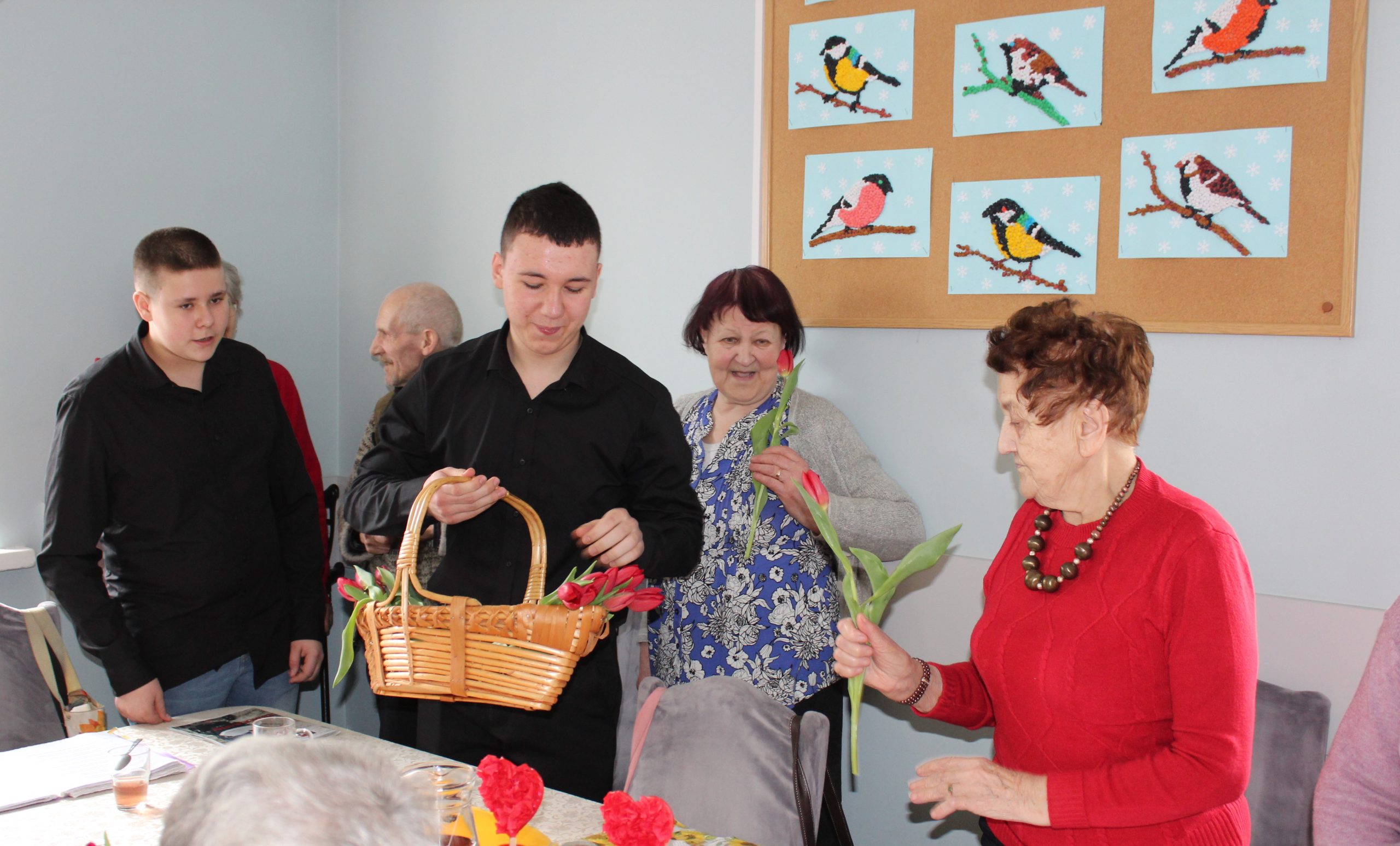 Na zdjęciu widzimy chłopców podchodzących do Seniorki by wręczyć jej kwiatka