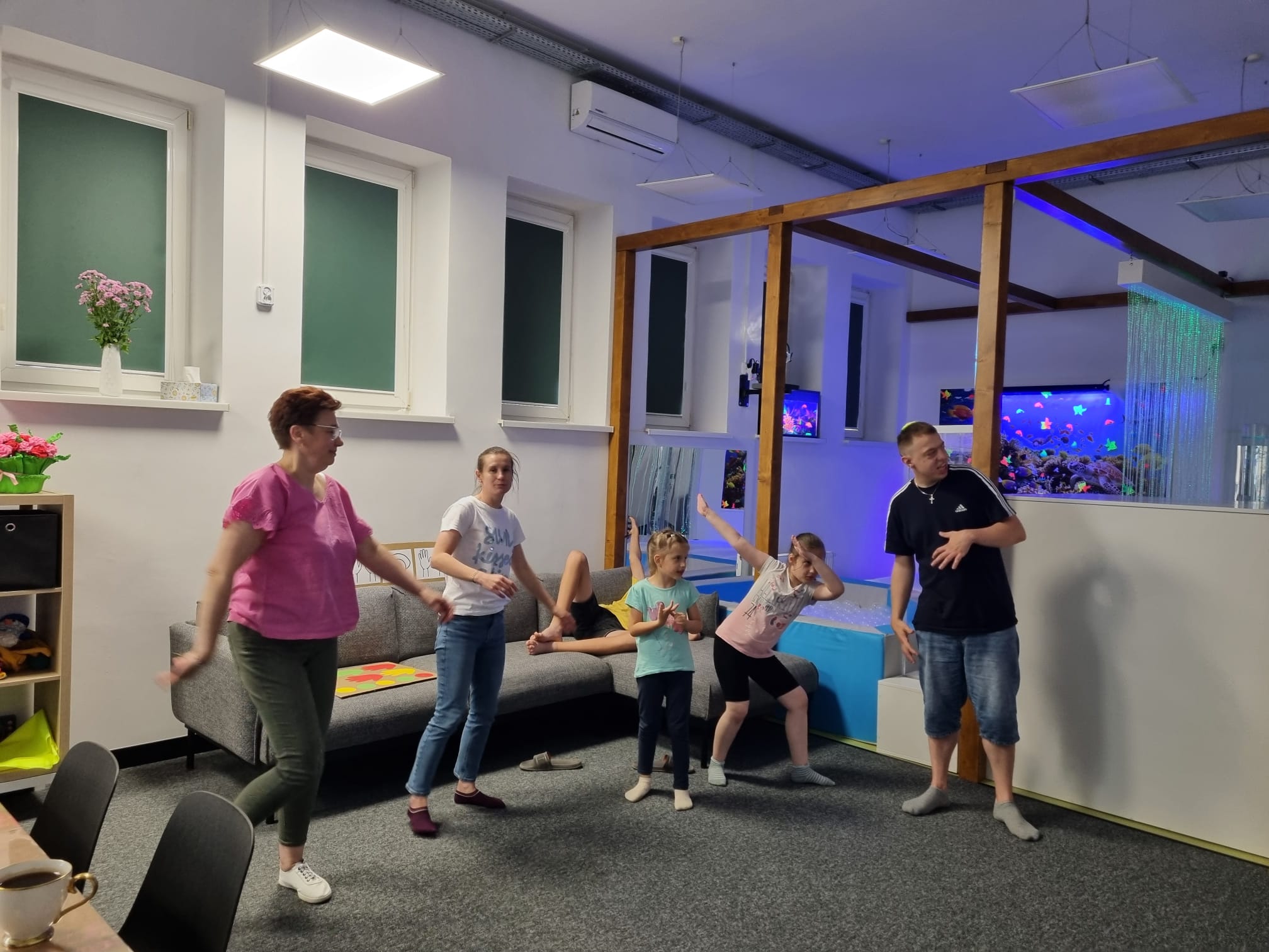 4) Zdjęcie wykonane na sali głównej dziennego centrum wsparcia, przedstawia terapeutów oraz uczestników podczas zajęć ruchowych.