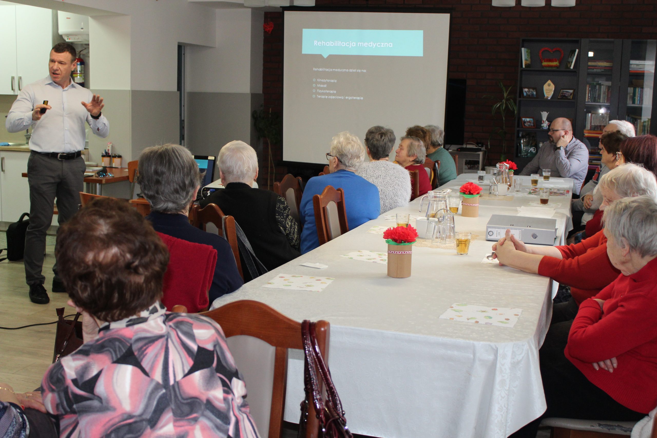 4) Na zdjęciu wykładowca tłumaczy seniorom definicje rehabilitacji medycznej.