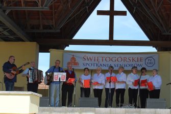 4) Na zdjęciu seniorzy na scenie plenerowej w Świętej Górze. Po lewej stronie dyrektor mgops grający na gitarze, uczestnik ddp grający na akordeonie oraz instruktor muzykoterapii grający na gitarze.