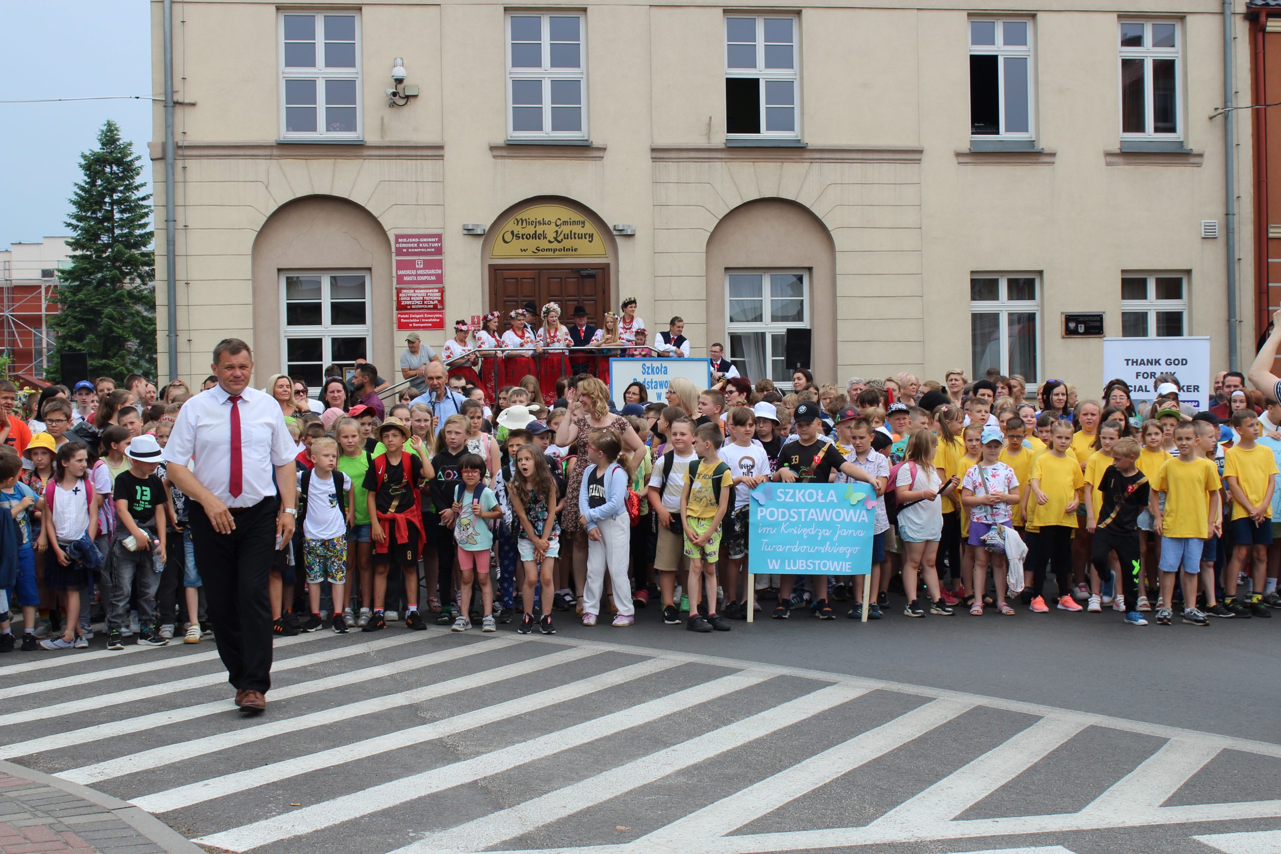 4) Zdjęcie przedstawia tłum mieszkańców biorących udział w teledysku do piosenki „Urodziny mojego miasta”. Po lewej stronie burmistrz miasta Sompolna. W tle miejsko – gminny ośrodek kultury.