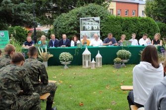 4) Fotografia przedstawia lektorów, a wśród nich Pana Romana Bednarka – burmistrza miasta Sompolna czytającego fragment powieści.