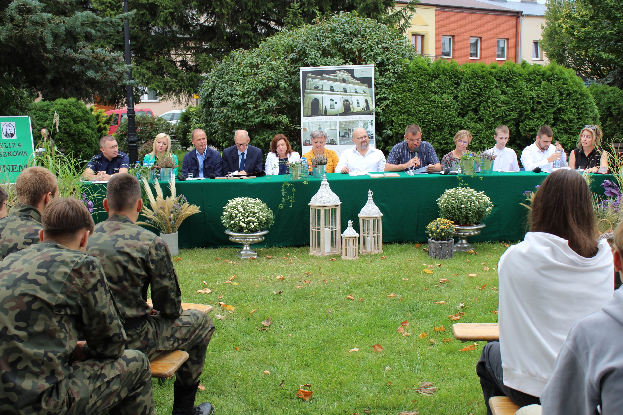 4) Fotografia przedstawia lektorów, a wśród nich Pana Romana Bednarka – burmistrza miasta Sompolna czytającego fragment powieści.