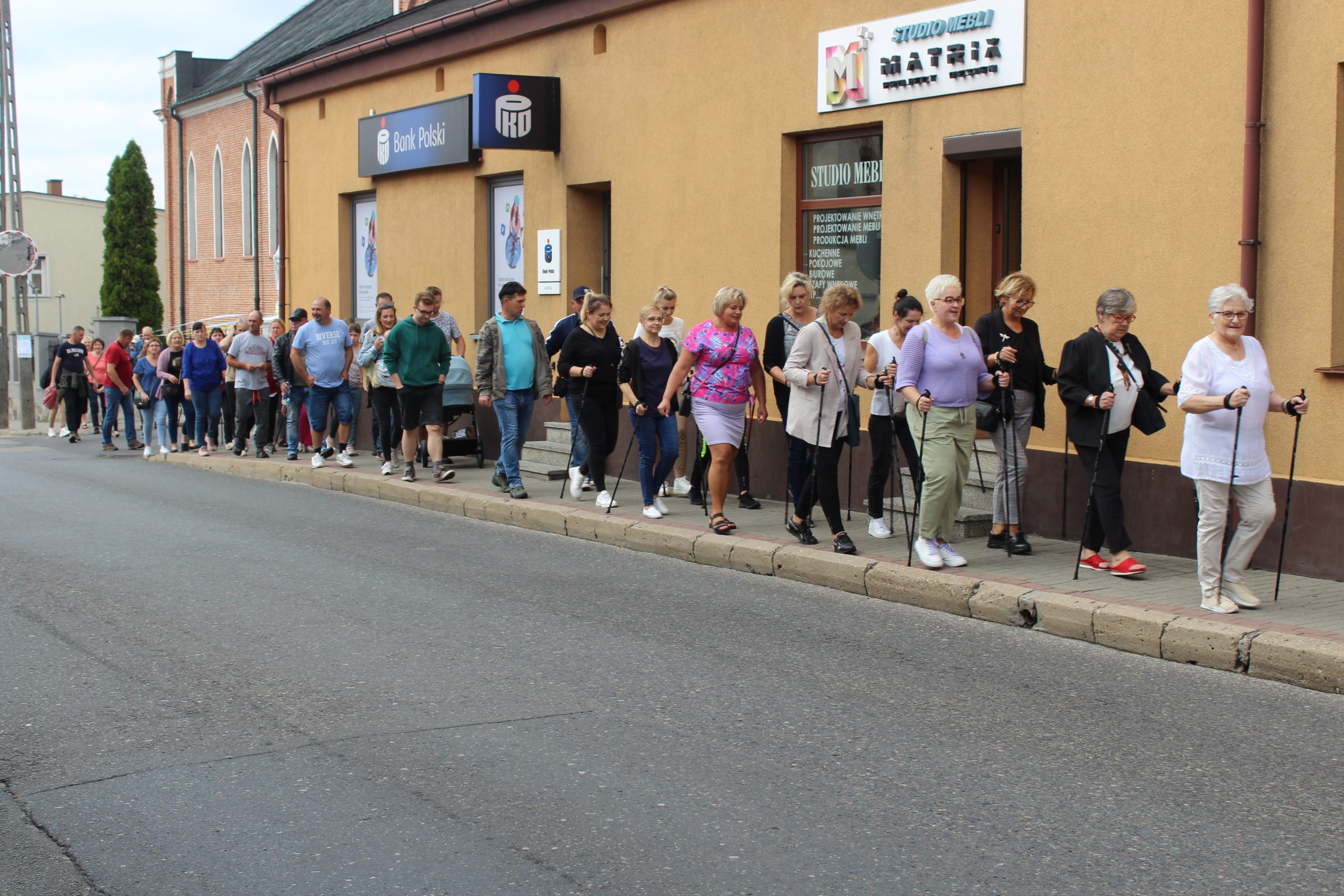 4) Na zdjęciu uczestnicy marszu nordic walking idący ulicą 11 Listopada.