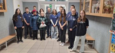 1) Zdjęcie wykonane na korytarzu szkoły w Mąkolnie. Przedstawia wolontariuszy i seniorów na zdjęciu grupowym.