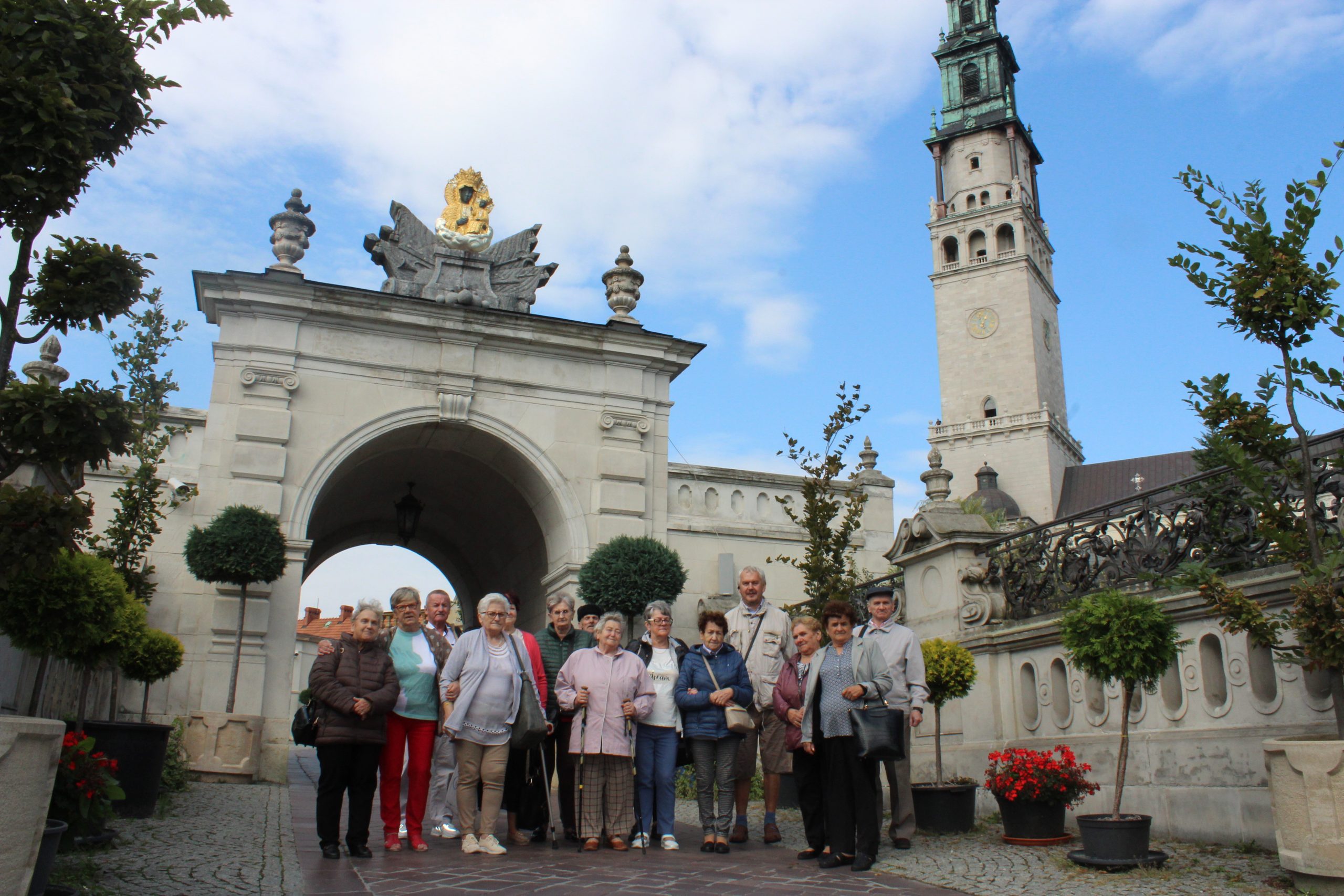 5) Na fotografii seniorzy na tle bramy wiodącej na Jasną Górę