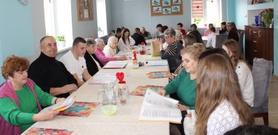 Zdjęcie przedstawia wszystkich zgromadzonych biesiadujących razem przy wspólnym stole.