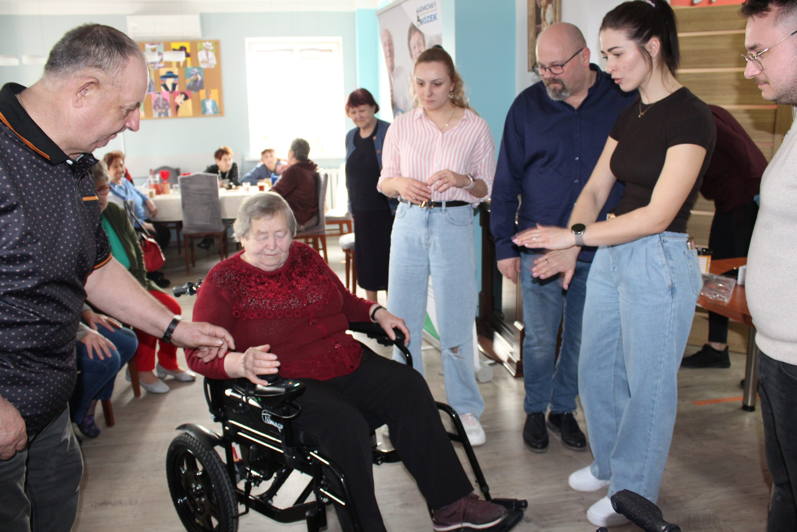 Na zdjęciu jedna z uczestniczek ddp siedząca na wózku elektrycznym. Wokół seniorzy z ddp oraz pracownicy mgops w sompolnie.
