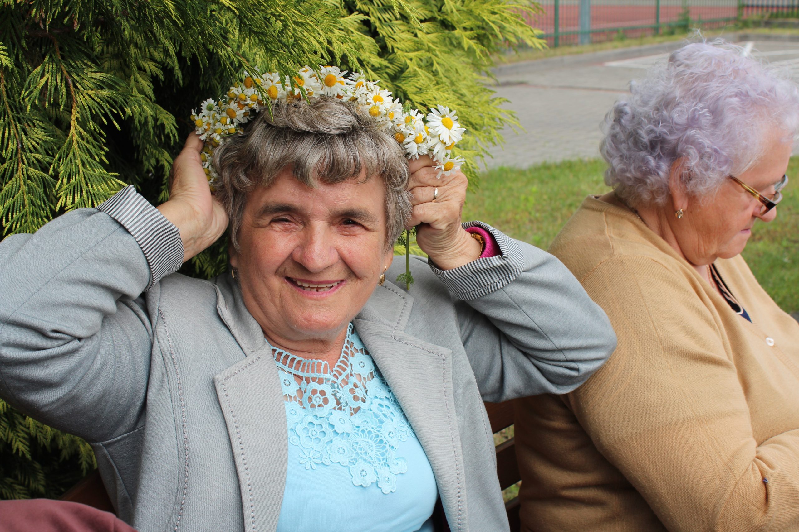 5) Fotografia przedstawia seniorkę z rumiankowym wiankiem na głowie