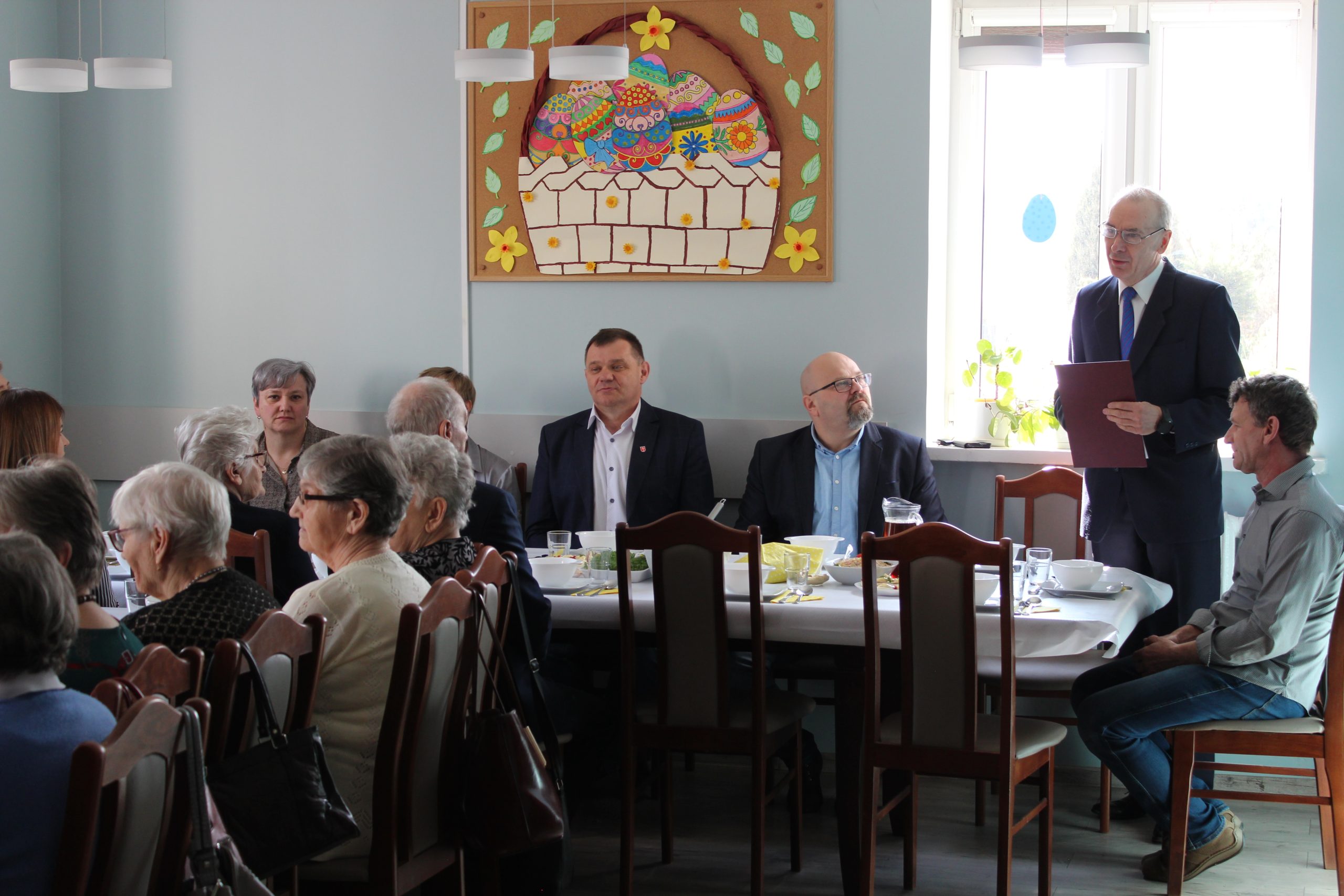 5 Na zdjęciu widać mężczyznę – jednego z zaproszonych gości, który w pozycji stojącej przemawia do wszystkich obecnych.