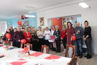 5. Zdjęcie grupowe wykonane na sali głównej Domu Dziennego Pobytu, przedstawiające Seniorów wraz z wolontariuszami oraz Dyrektorem MGOPS.