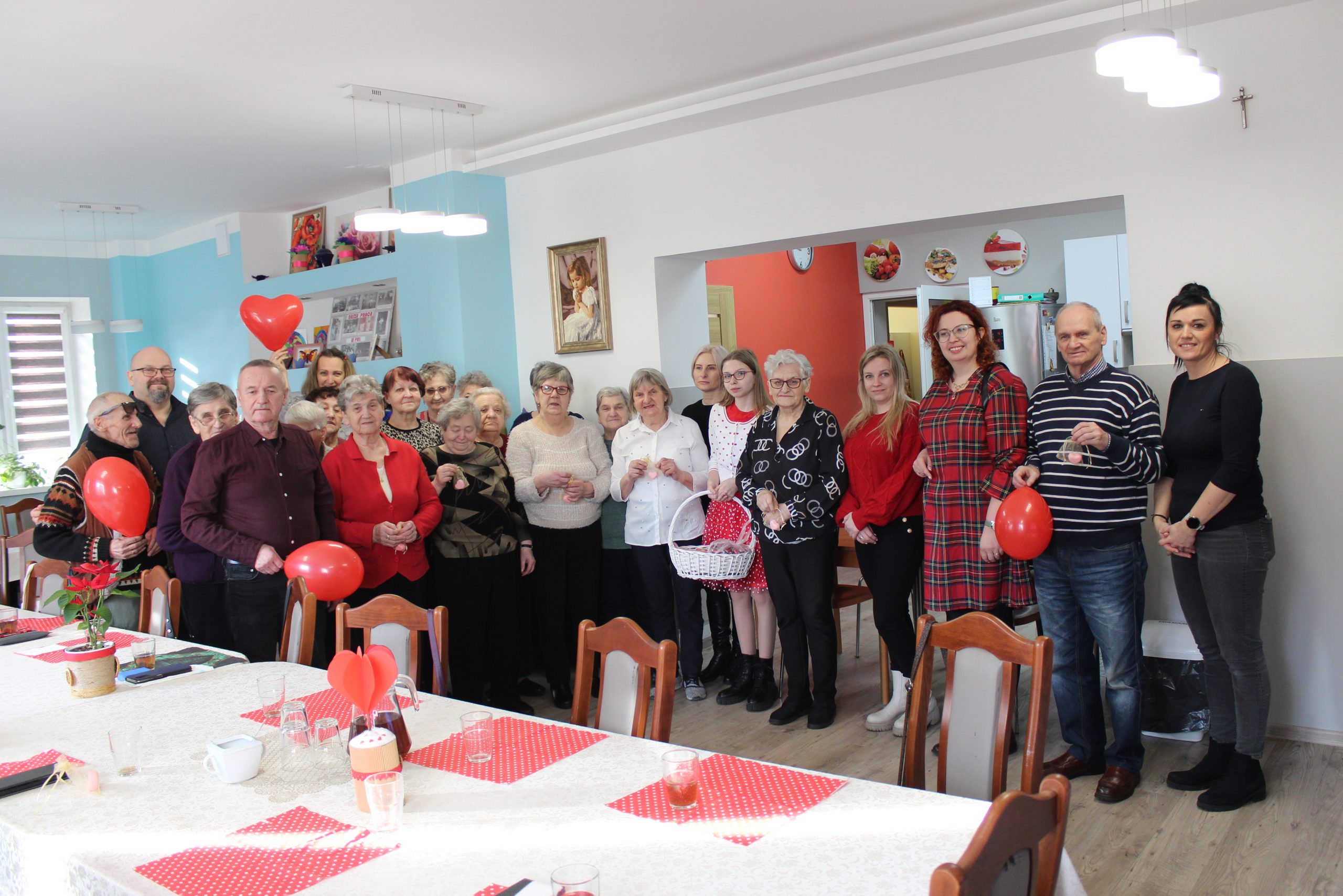 5. Zdjęcie grupowe wykonane na sali głównej Domu Dziennego Pobytu, przedstawiające Seniorów wraz z wolontariuszami oraz Dyrektorem MGOPS.