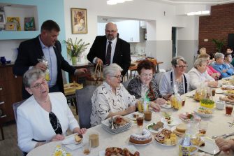 5) Na fotografii burmistrz wraz z dyrektorem wręczają upominki seniorom.