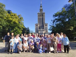 5) Na fotografii grupa seniorów wraz z opiekunami przy Pałacu Kultury.