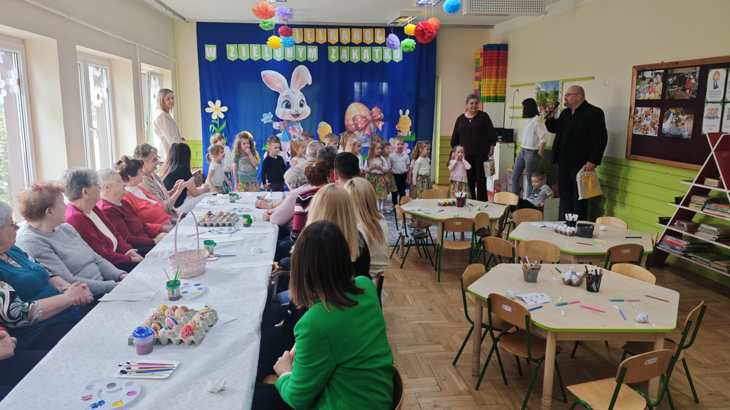 2. Zdjęcie wykonane w sali przedszkolnej podczas przedstawienia przygotowanego przez dzieci oraz dyrektora Miejsko-Gminnego Ośrodka Pomocy Społecznej w Sompolnie wręczającego dzieciom prezent od Zająca Wielkanocnego.