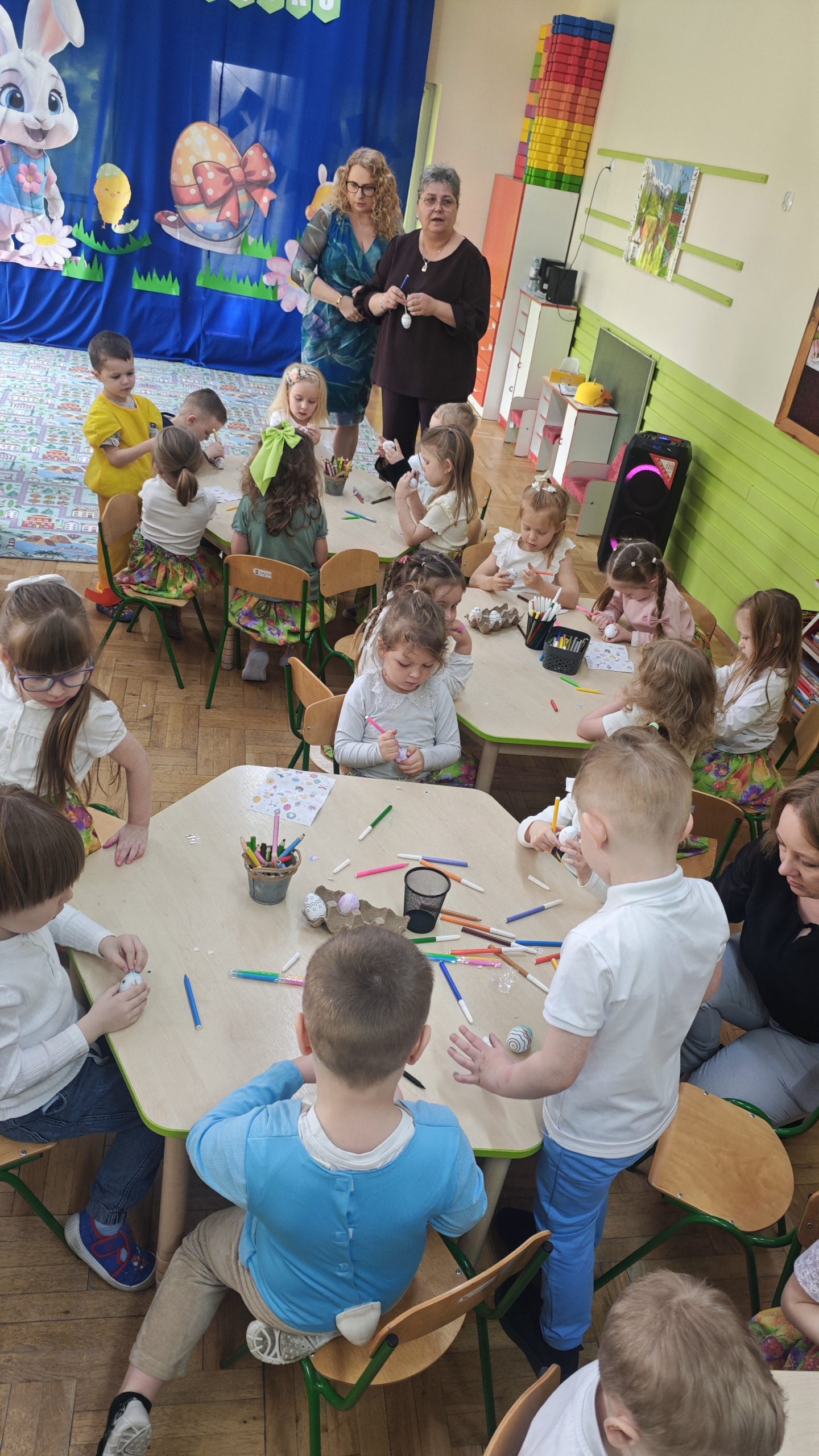 6. Zdjęcie przedstawia dzieci wykonujących dekoracje na pisankach.