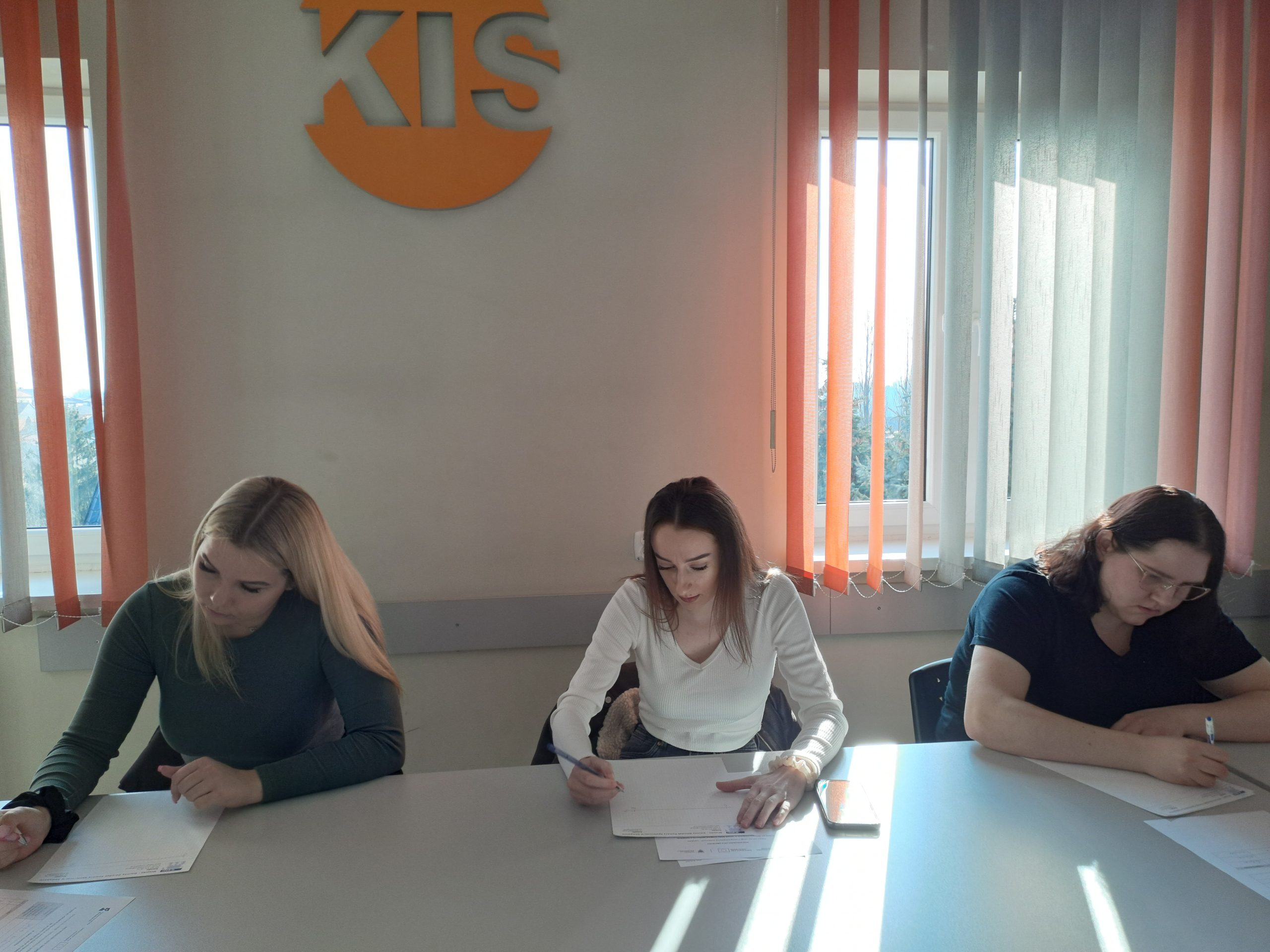 Na zdjęciu widzimy trzy kobiety, które w skupieniu robią notatki w trakcie szkolenia